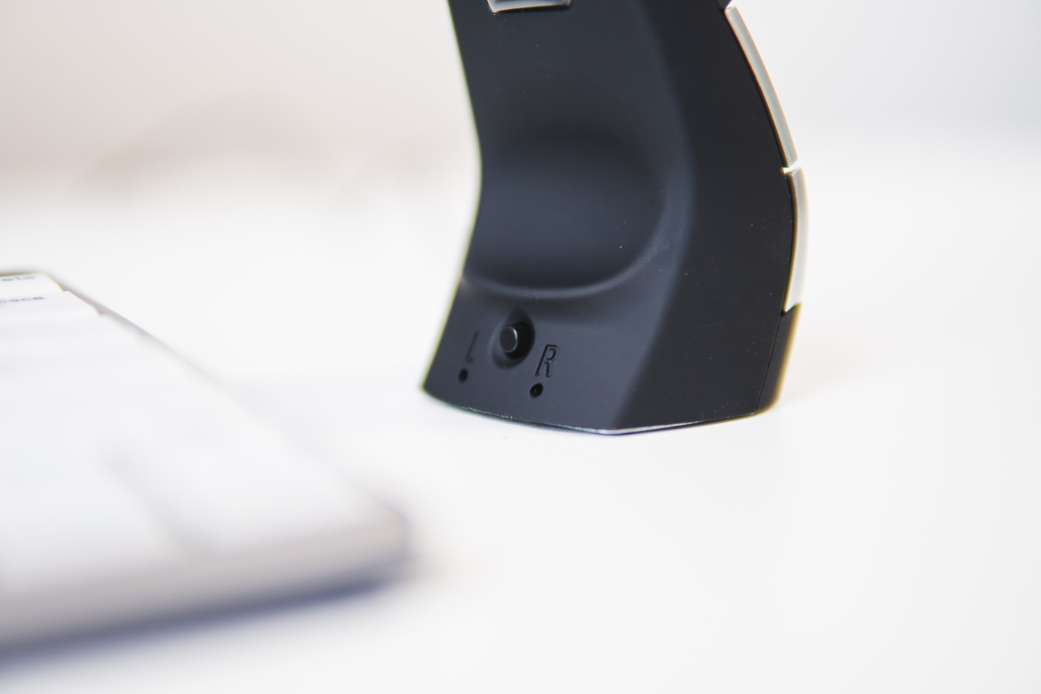 Close-up of a black mouse. Shows the side with buttons and the letters L and R.