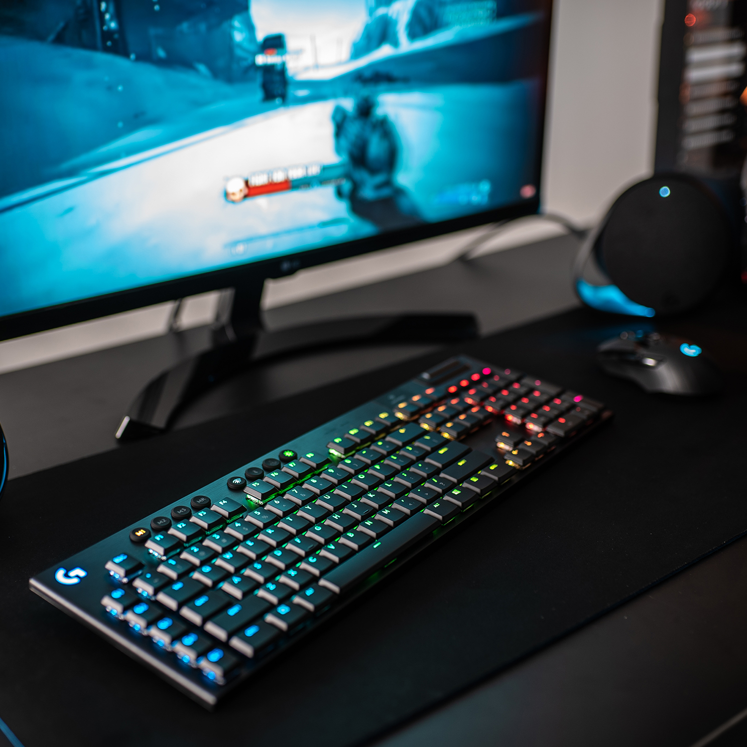 Gaming setup met toetsenbord, monitor met game en muis. RGB-verlichting op toetsenbord.