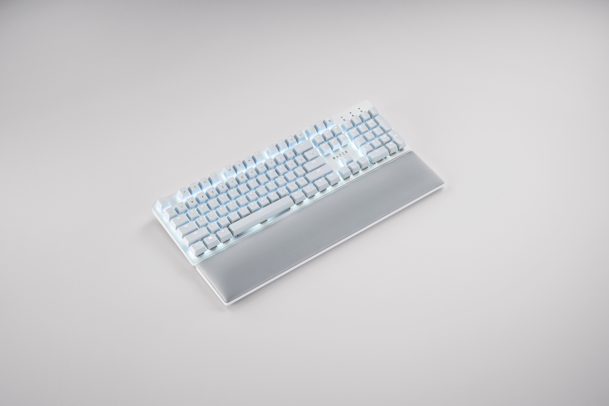 Clavier de jeu blanc avec touches éclairées et repose-poignets, sur une surface gris clair.