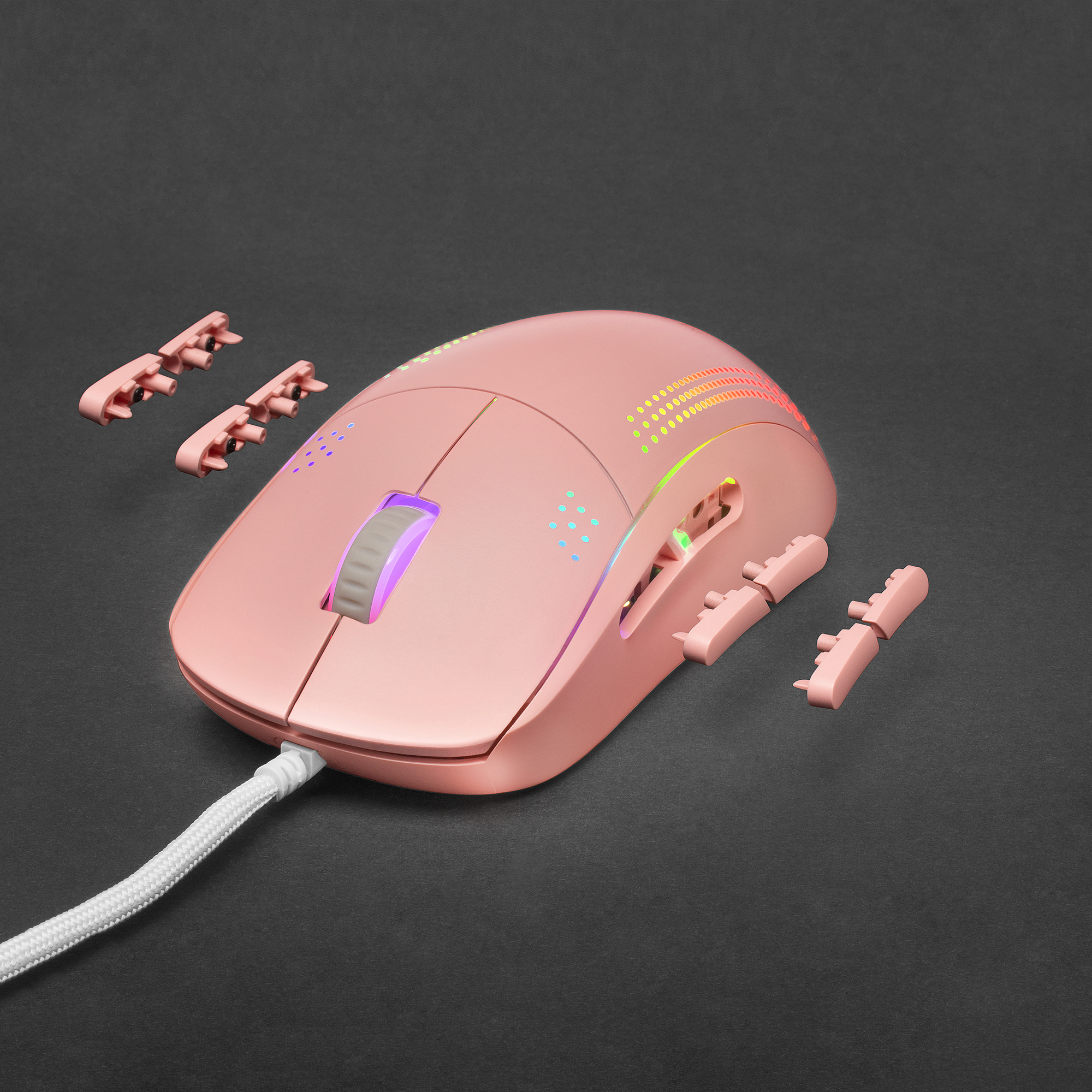 Roze gamingmuis met extra roze knoppen. De muis ligt op een zwart oppervlak. Er zijn veelkleurige lichten.