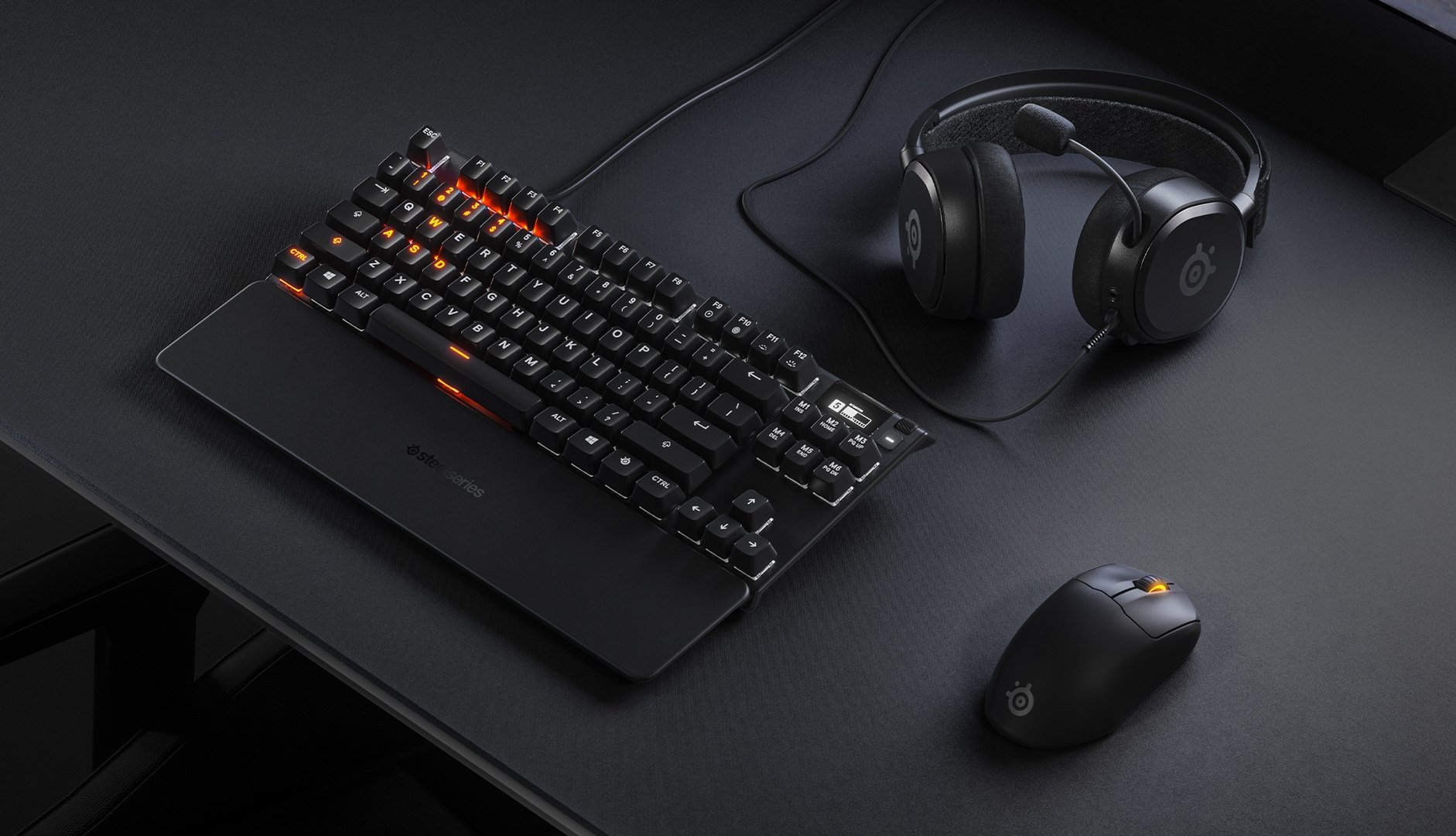 Schwarze Tastatur mit orangefarbenen Tasten, Kopfhörer und Maus auf schwarzem Grund.