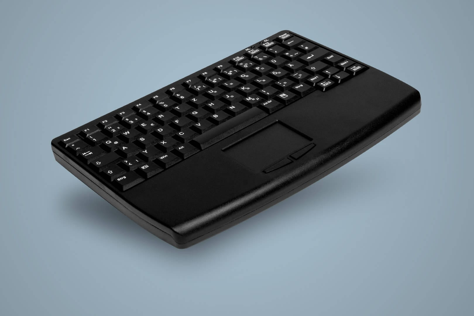 Tastiera nera con touchpad sul lato destro, su una superficie blu-grigio.