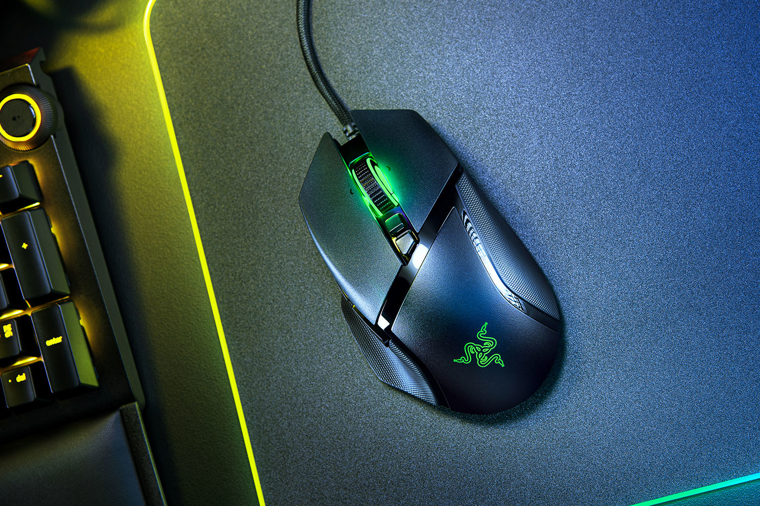 Mouse da gioco nero su un tappetino blu e giallo. Luce verde sulla rotella, logo visibile.
