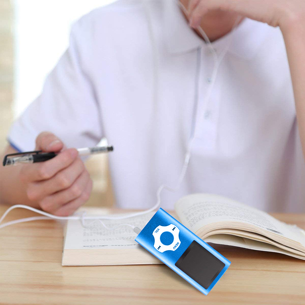 Eine Person hält einen blauen MP3-Player mit Ohrhörern. Ein Buch ist auf einem Holztisch geöffnet.