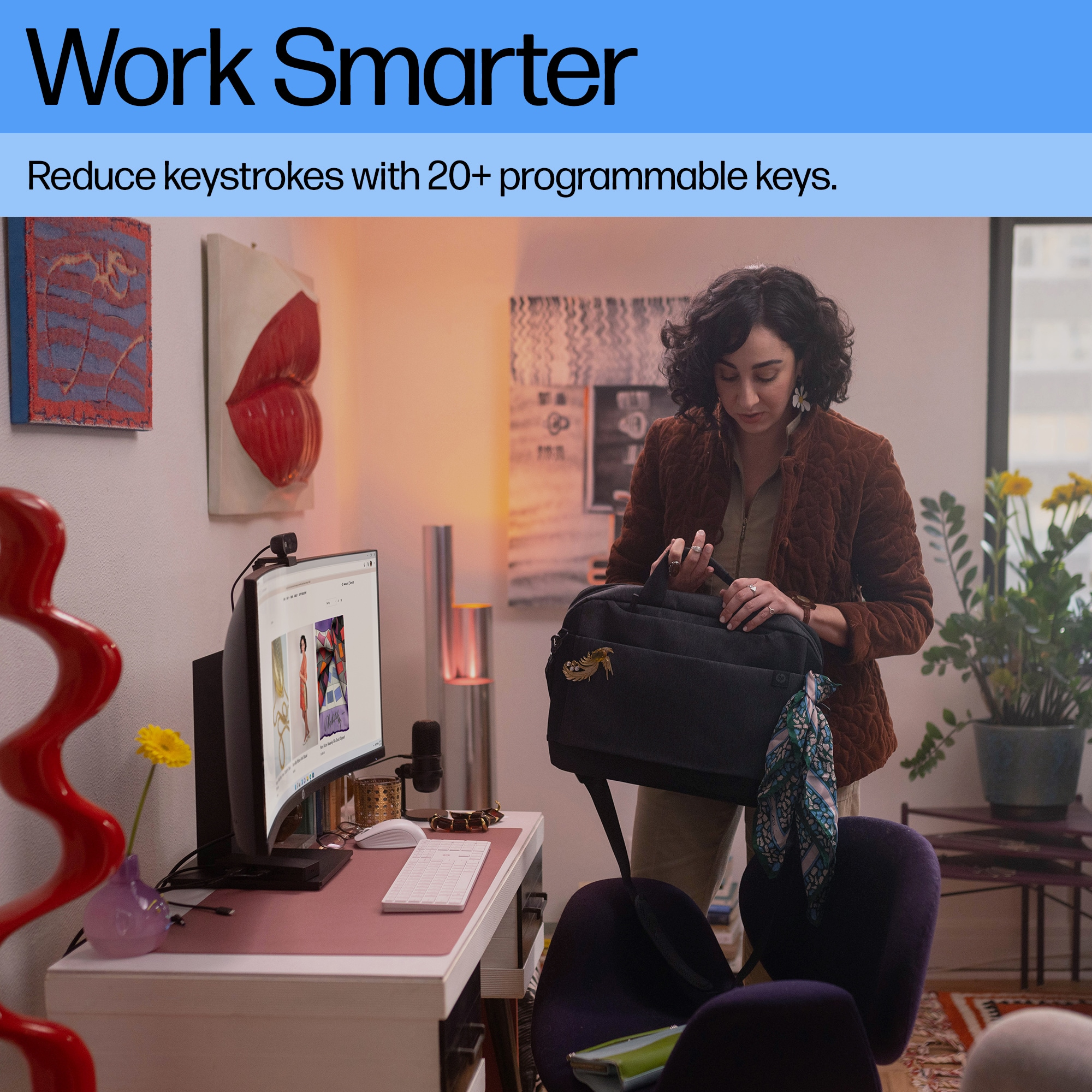Frau arbeitet an einem Schreibtisch mit Computer und Tastatur. Eine Tasche liegt auf dem Tisch.