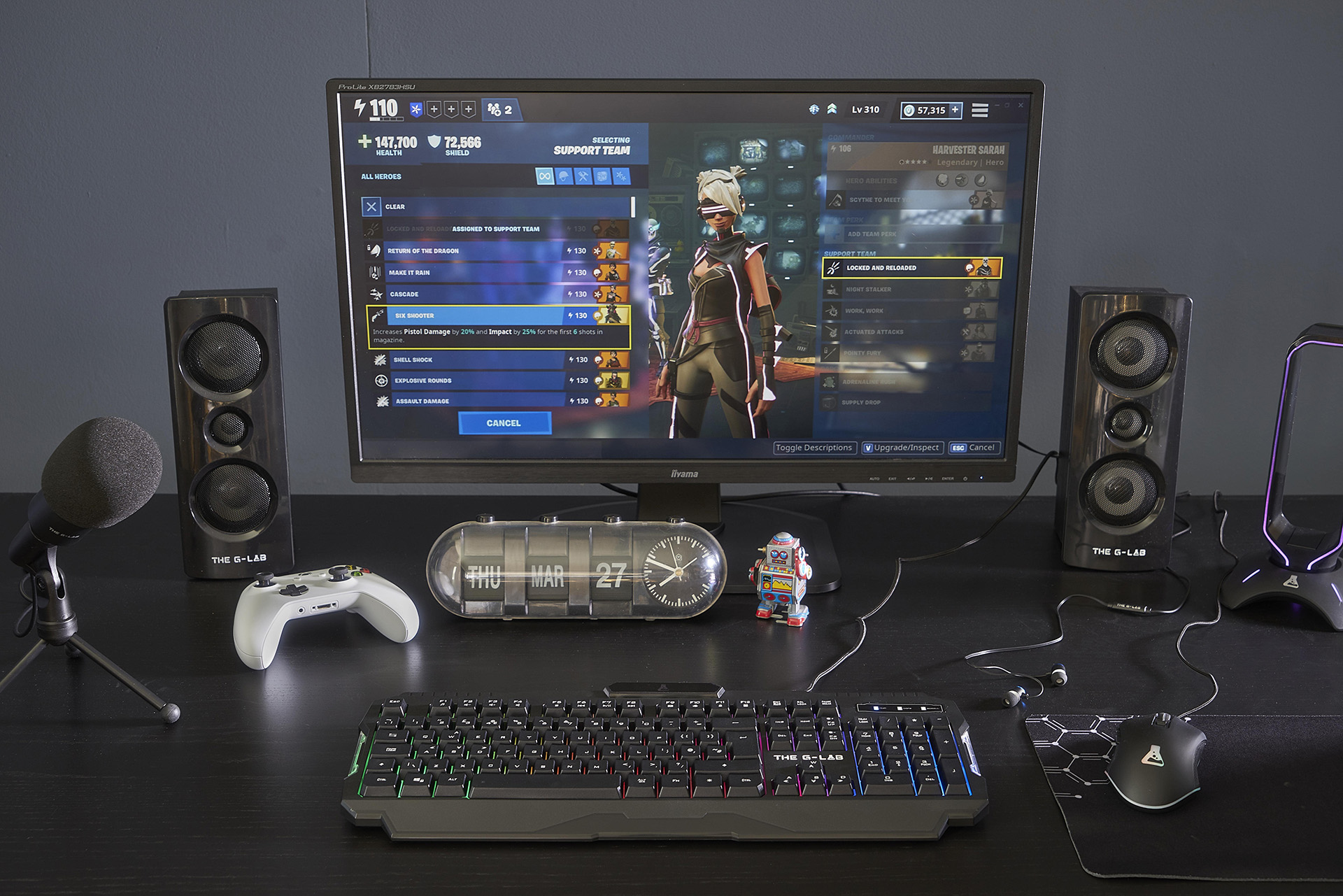 Biurko z konfiguracją do gier. Zawiera monitor, głośniki, klawiaturę, mysz, mikrofon i kontroler.