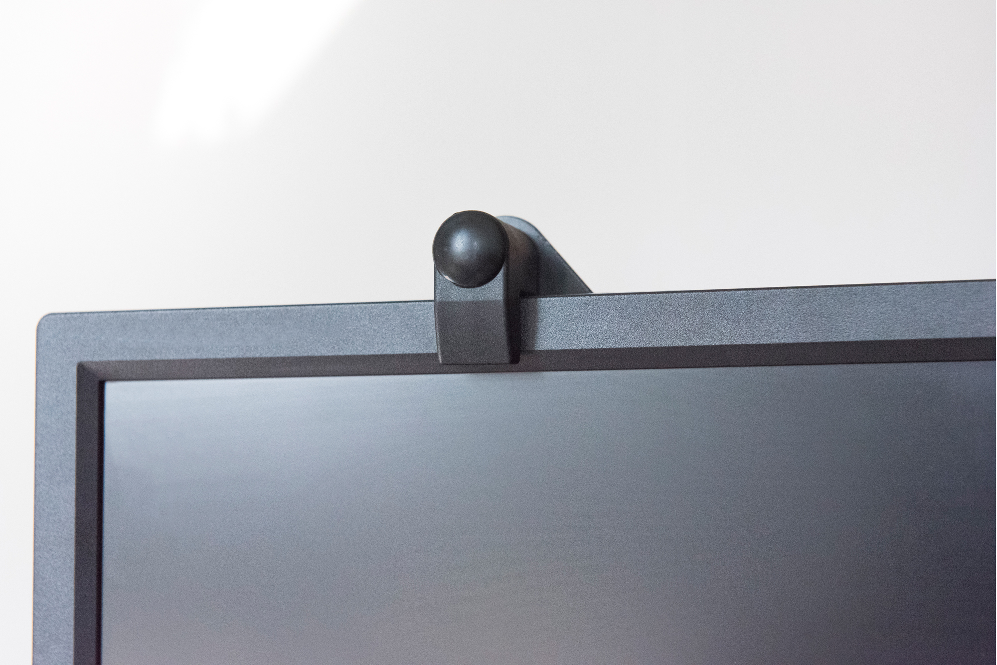 Schwarzer Computermonitor mit einer Webcam oben befestigt. Weißer Hintergrund.