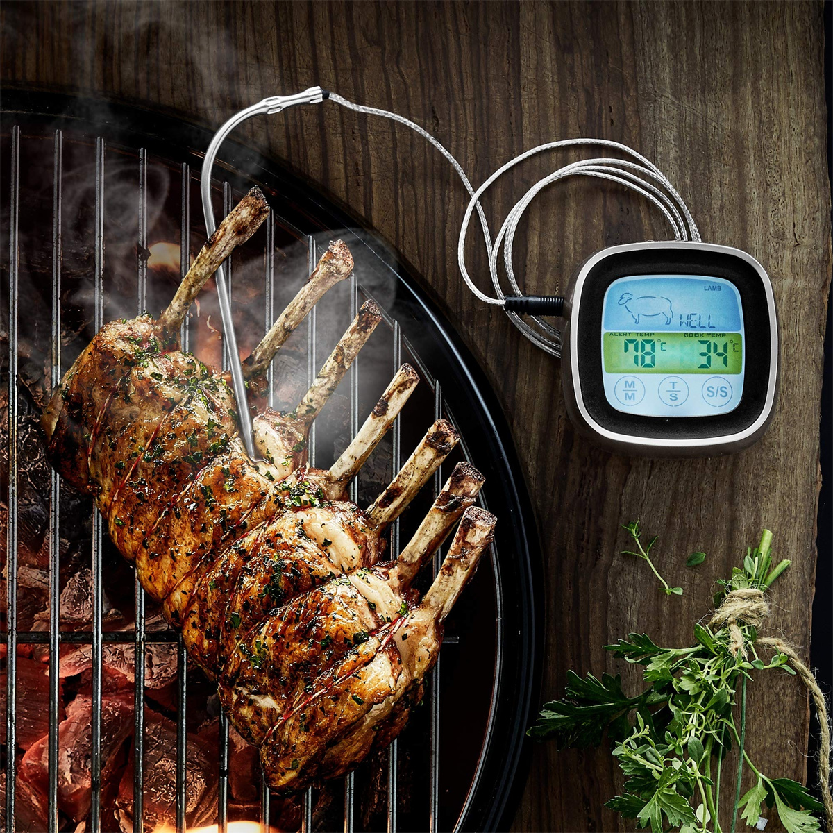 Lammkarree auf Grill mit Thermometer. Anzeige zeigt 78 °C. Holzoberfläche mit Kräutern.