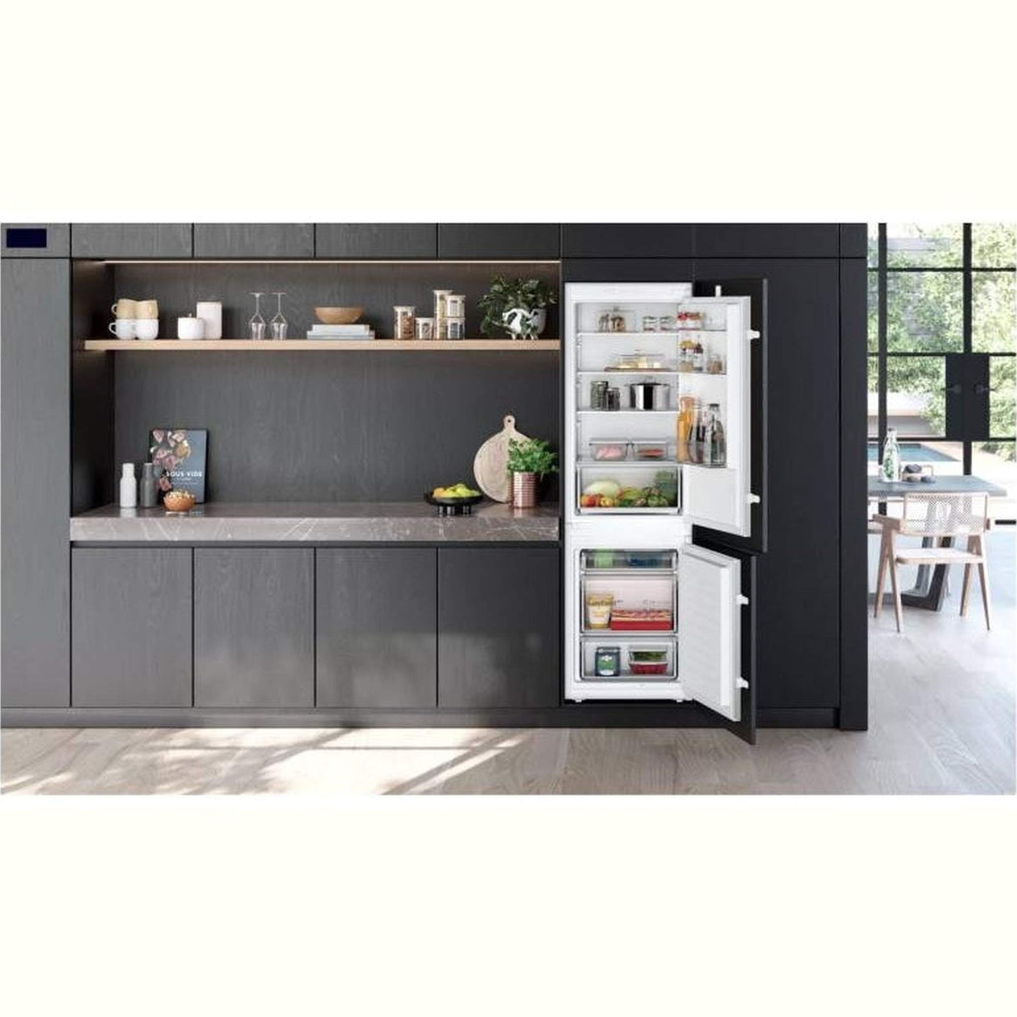 Kuchnia z wbudowaną lodówką z otwartymi drzwiami. Widoczne półki, jedzenie i blat. Ciemne odcienie.