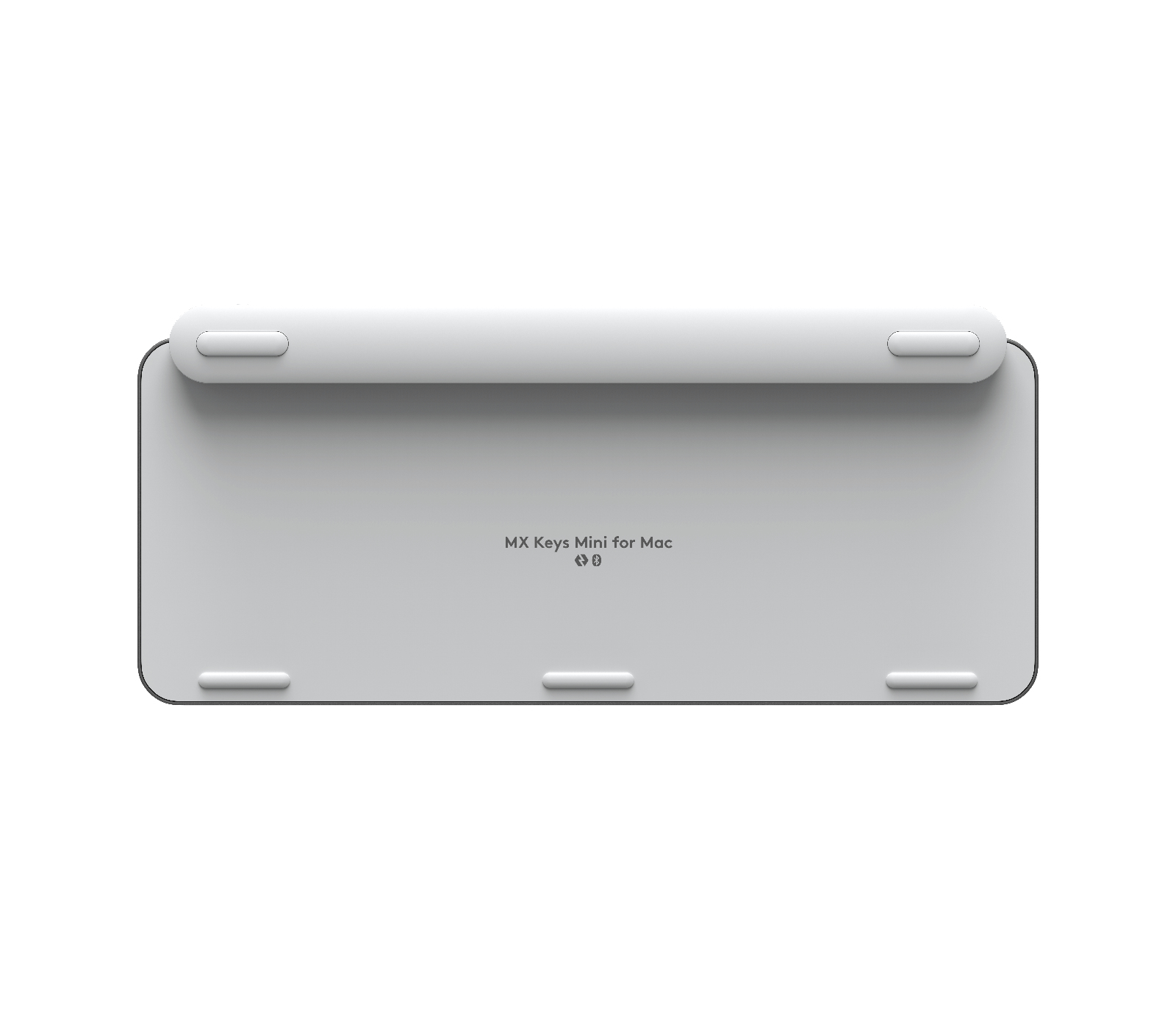 Biała klawiatura, widok od spodu. To mini klawiatura dla Maca, z gumowymi nóżkami.