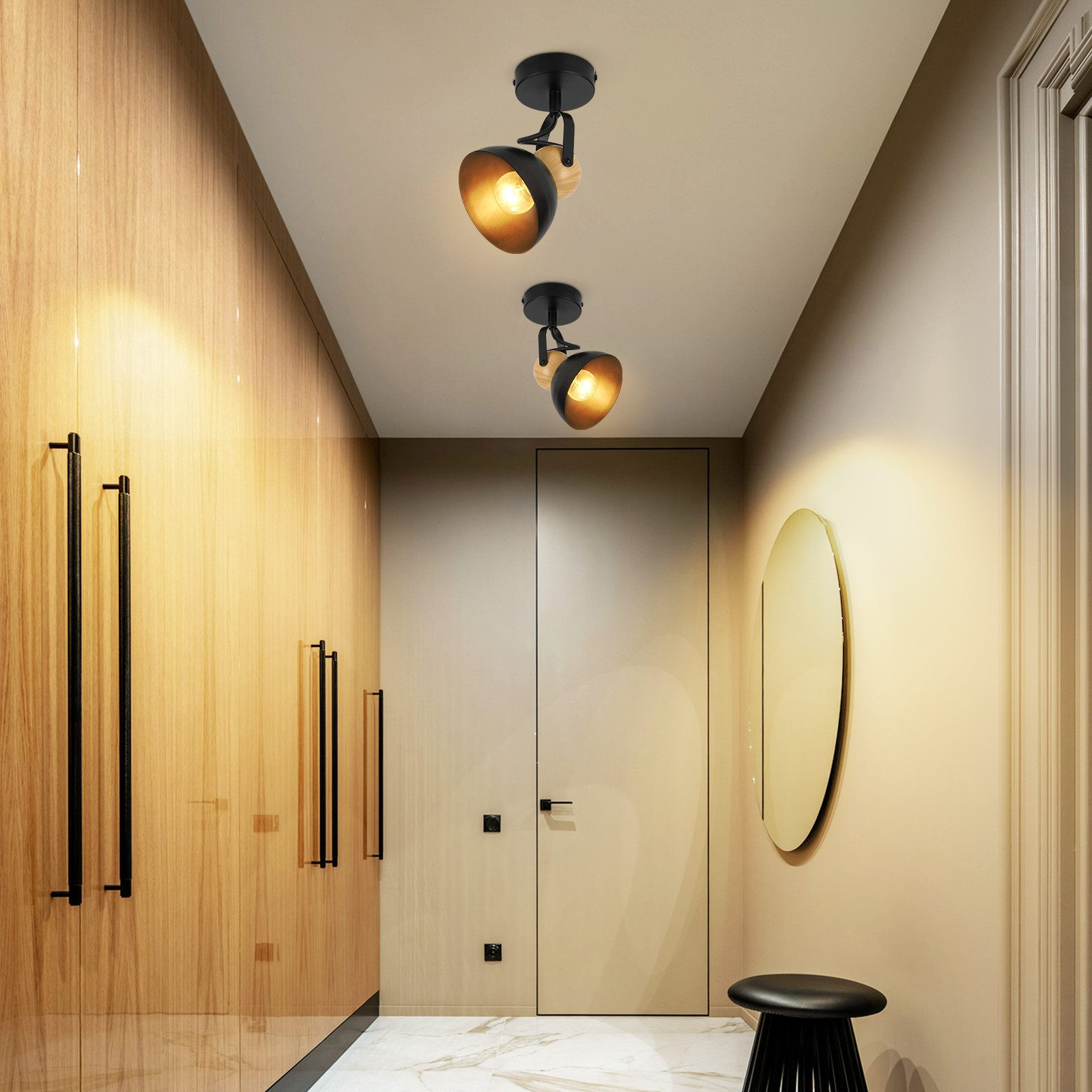 Korytarz z drewnianymi panelami i czarnymi akcentami. Dwie lampy wiszące oświetlają przestrzeń. Na ścianie lustro.