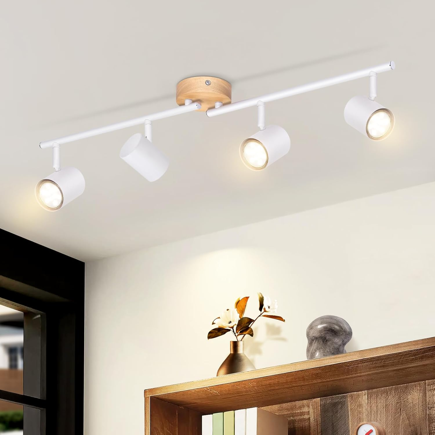 Białe reflektory sufitowe na białym torze, oświetlające półkę z dekoracjami.