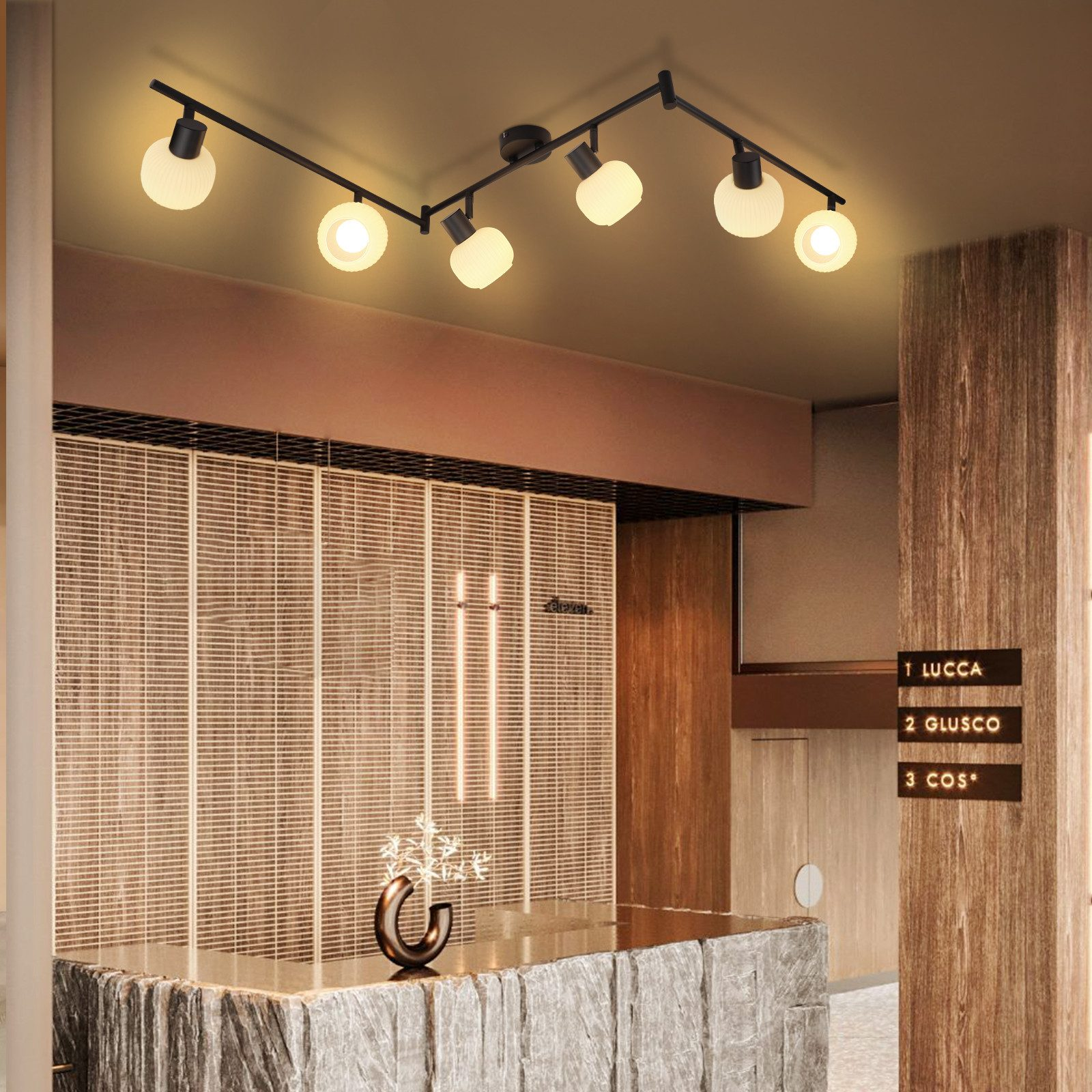 Nowoczesna lampa sufitowa. Czarna rama z wieloma oprawami oświetleniowymi. Wnętrze z recepcją.