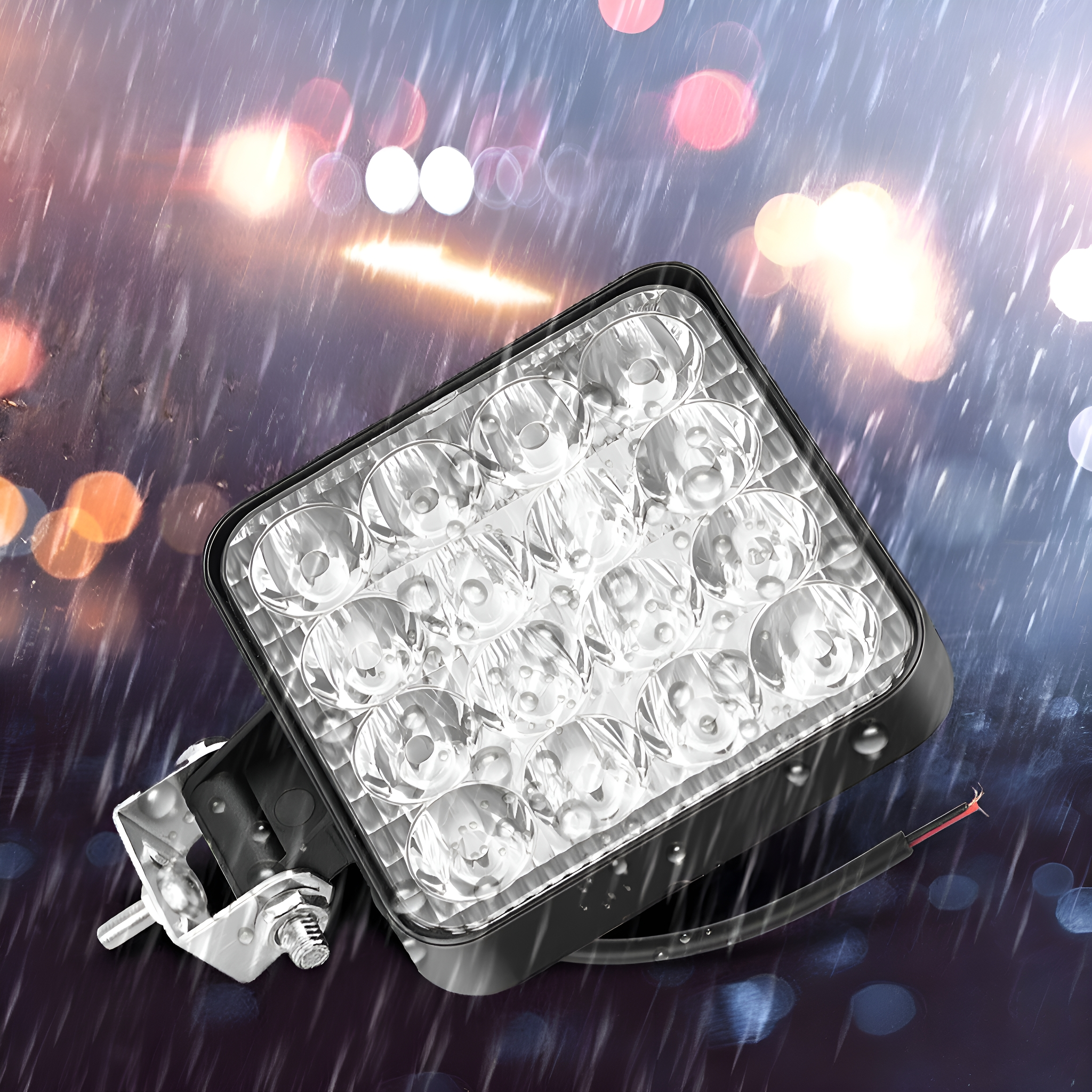 Quadratischer LED-Scheinwerfer mit schwarzem Rahmen, im Regen mit Wassertropfen darauf.