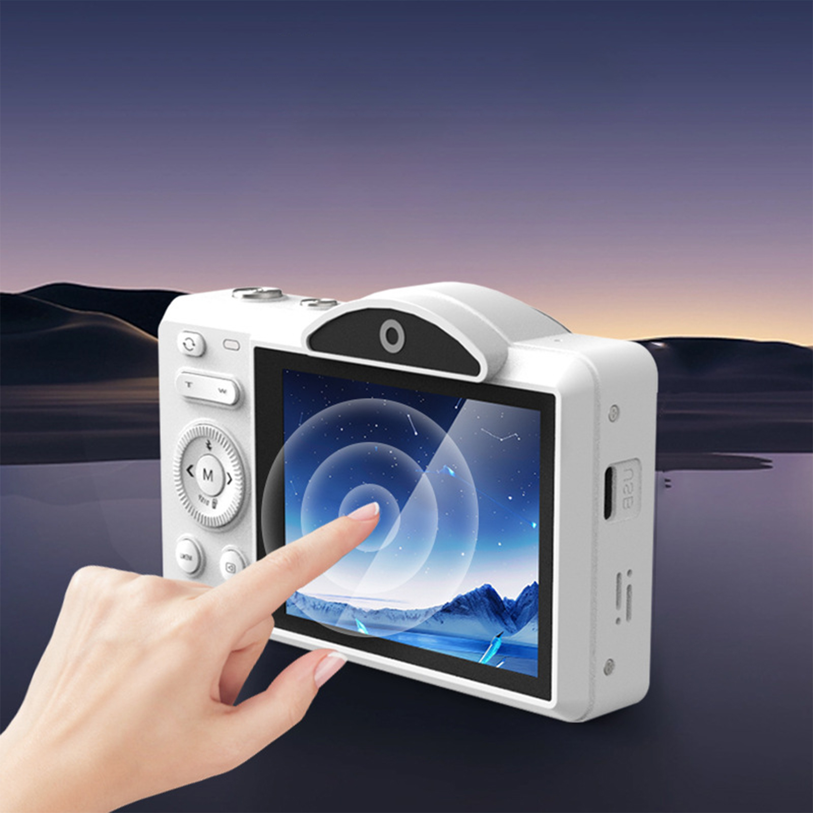 Weiße Digitalkamera, ein Finger berührt den Bildschirm. Hintergrund zeigt eine verschwommene Landschaft.