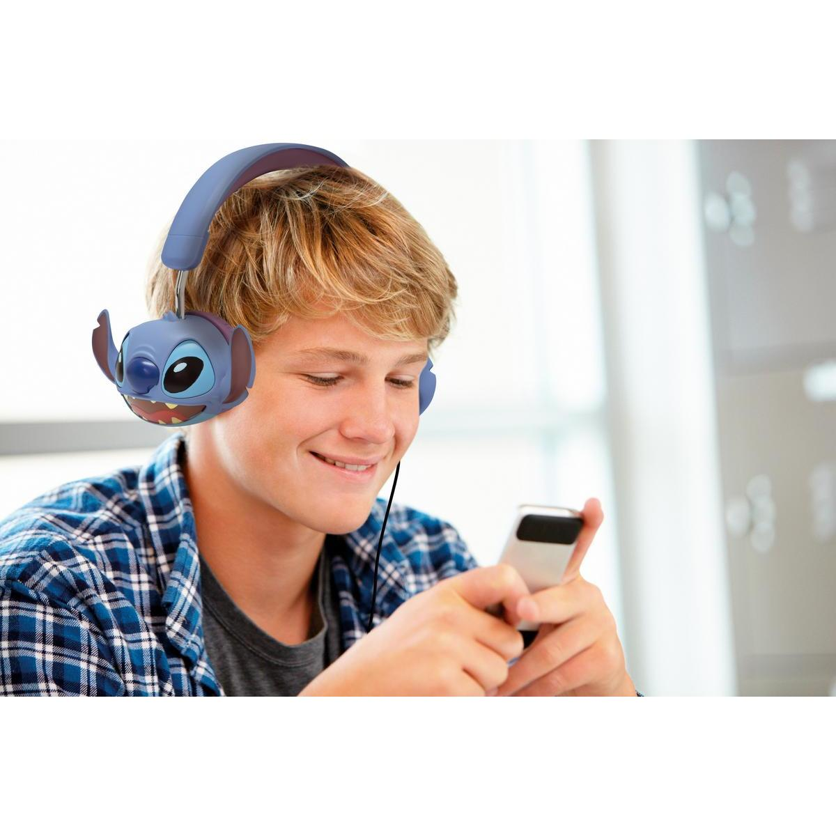 Nastolatek w słuchawkach Stitch, trzymający telefon i uśmiechnięty.
