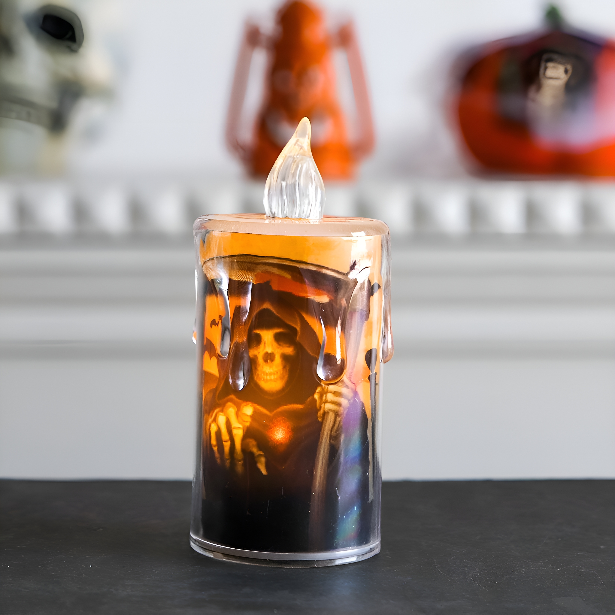 Eine Halloween-Kerze mit Totenkopf, orangefarbenen Wachstropfen und flackernder Flamme.