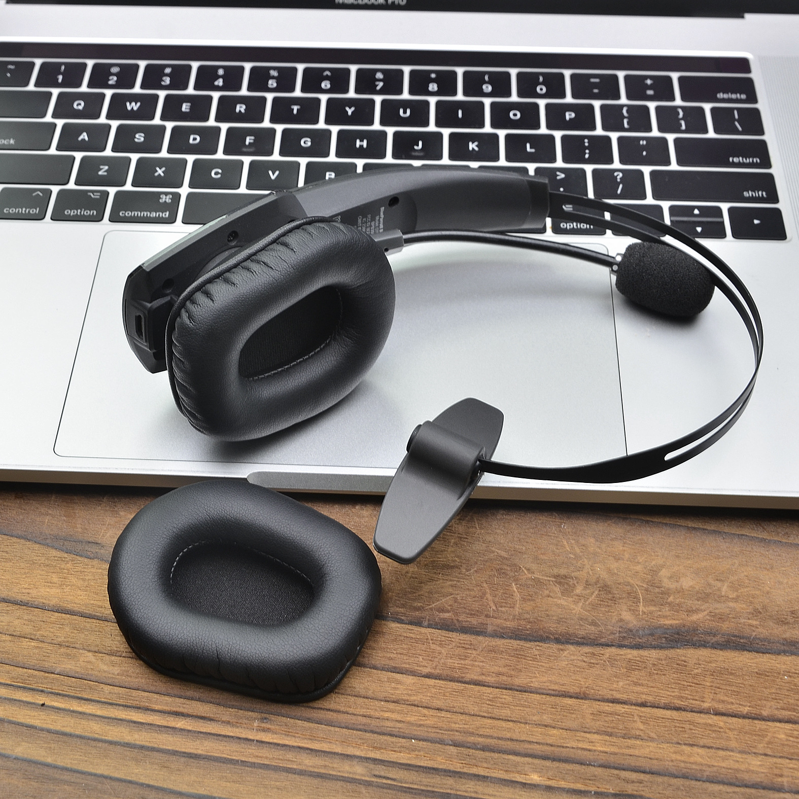 Cuffie nere con cuscinetti auricolari rimovibili e microfono, posizionate sulla tastiera di un laptop.