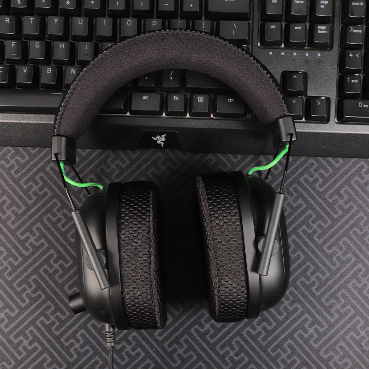 Cuffie da gioco nere su tastiera nera. Dettagli del cavo verde, vista dall'alto.