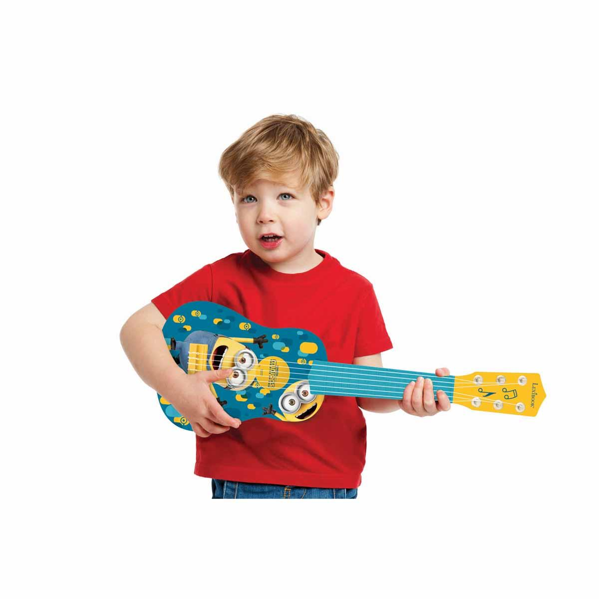 Mały chłopiec trzymający zabawkowe ukulele. Ukulele ma wzór Minionków.