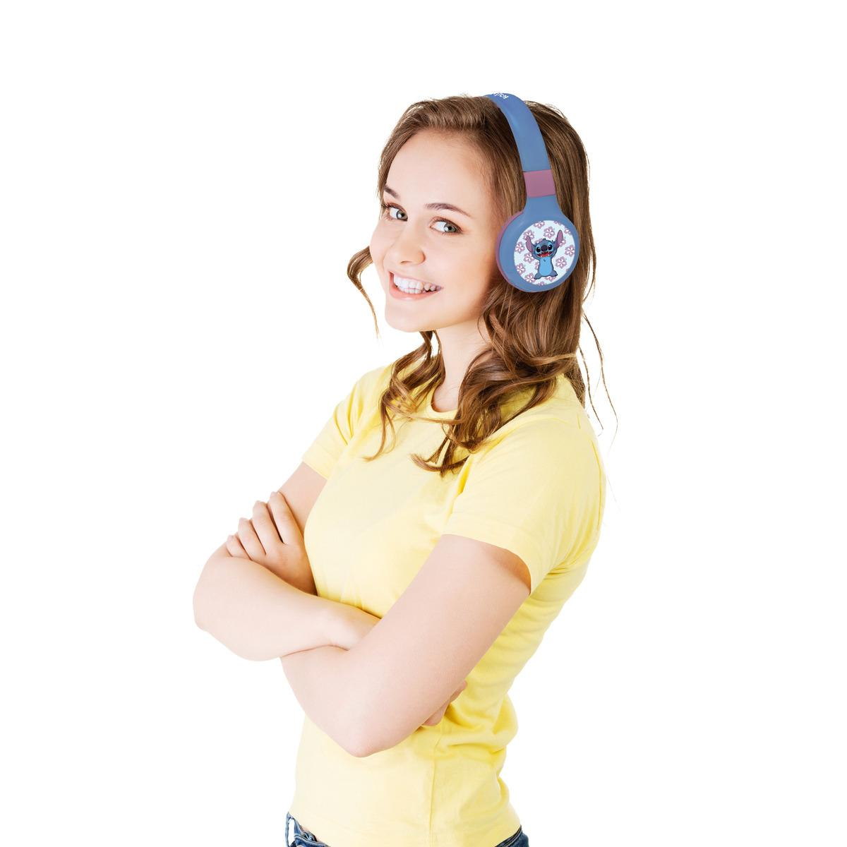 Młoda kobieta w żółtej koszulce i słuchawkach Stitch, uśmiechnięta, z założonymi rękami.