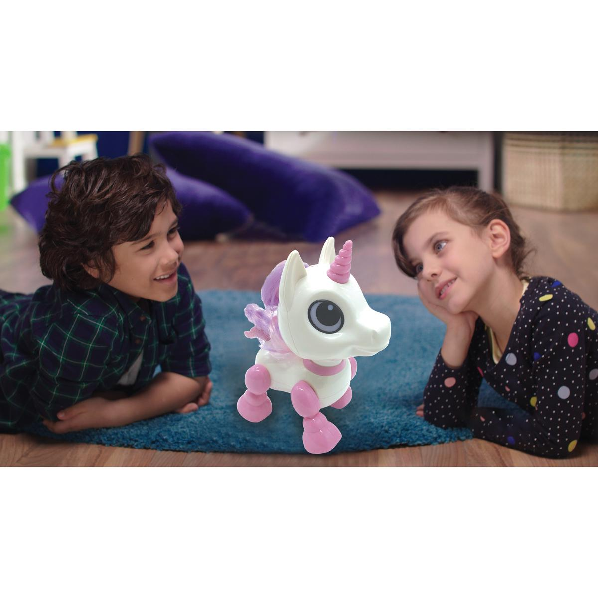 Dos niños mirando un juguete de unicornio. El juguete está en una alfombra azul.