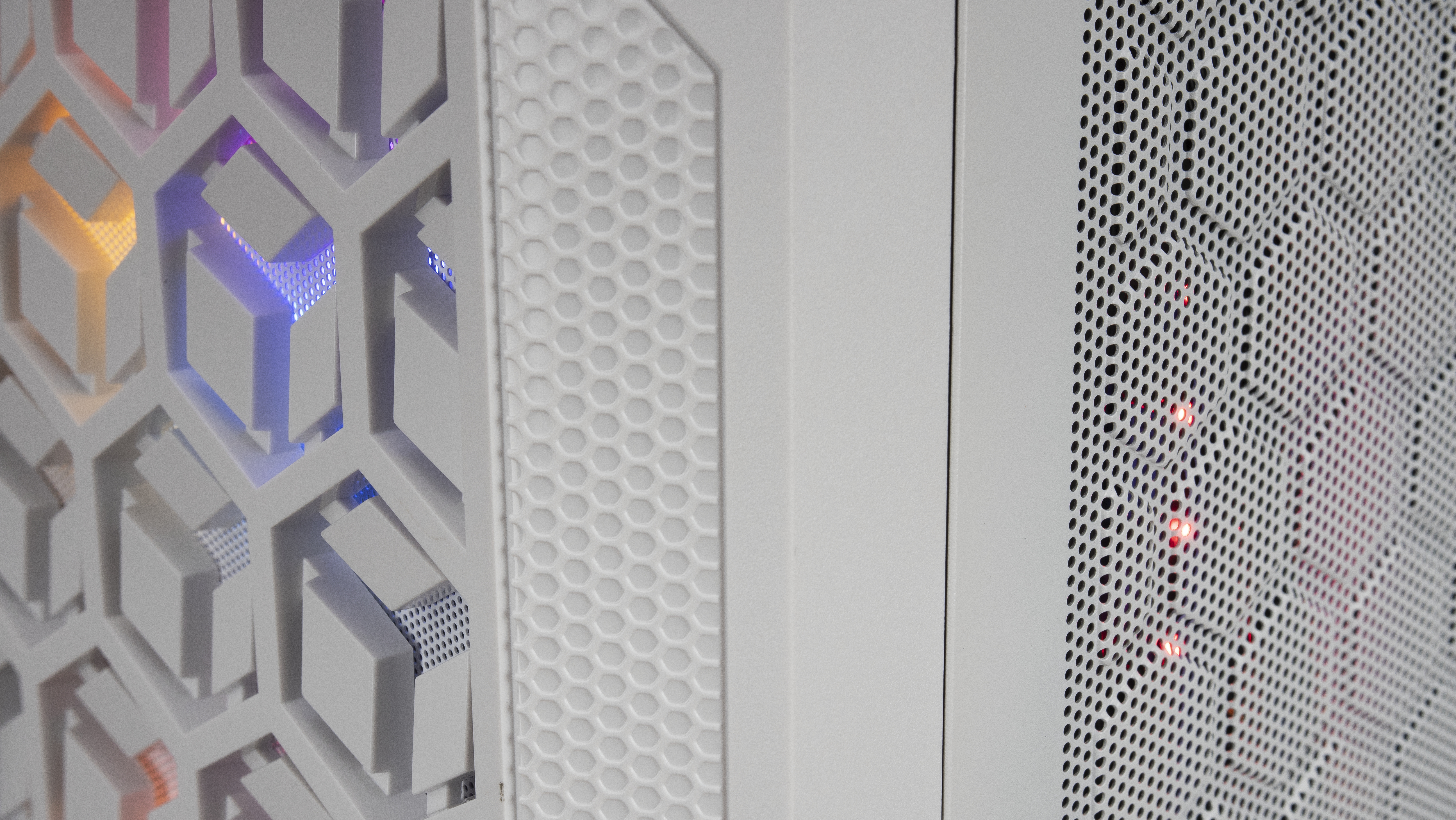 Dettagli del case del computer bianco: pannelli a nido d'ape, forati e solidi con luci RGB interne.