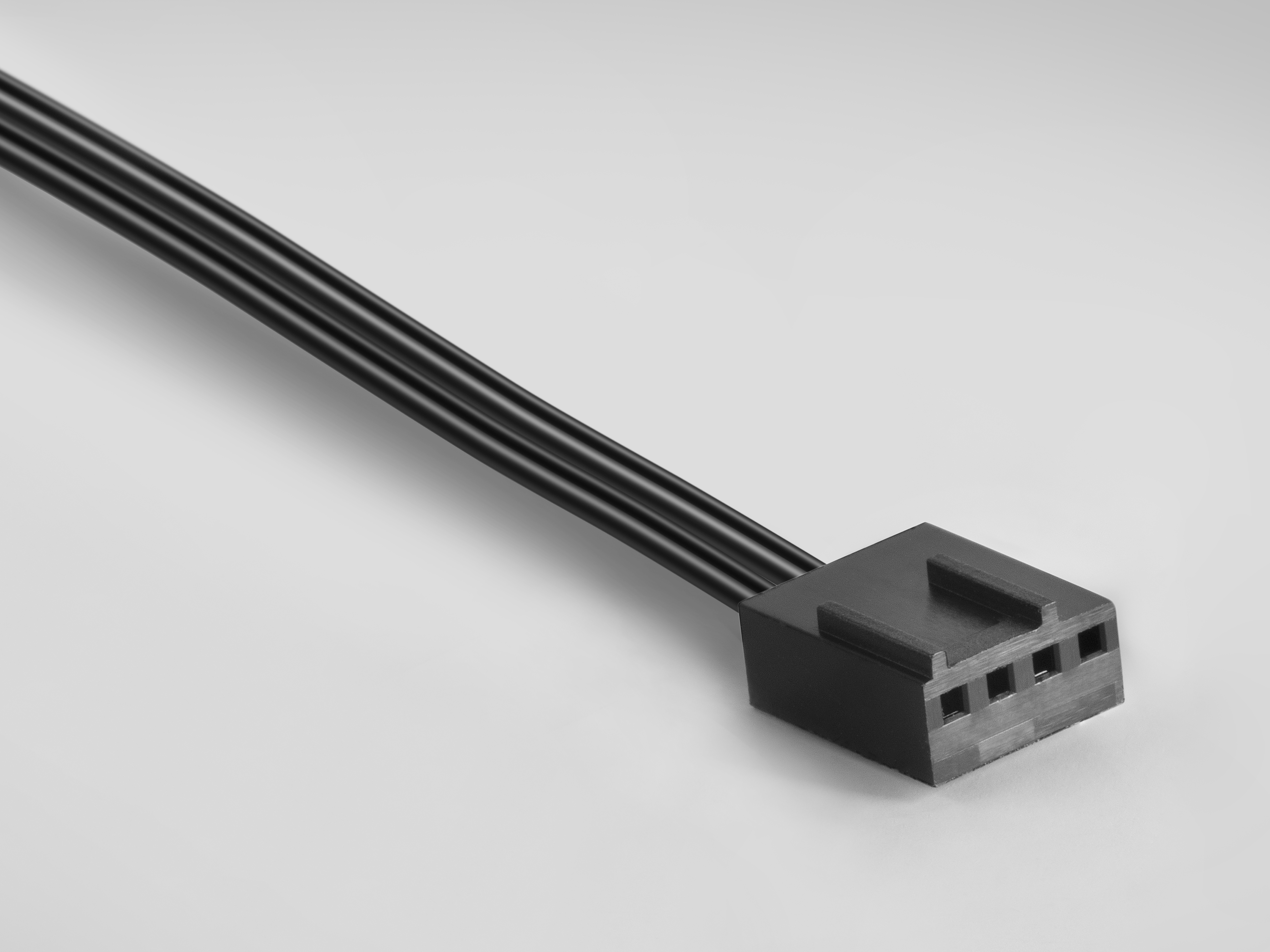 Conector de ventilador negro con 3 cables, sobre una superficie clara.