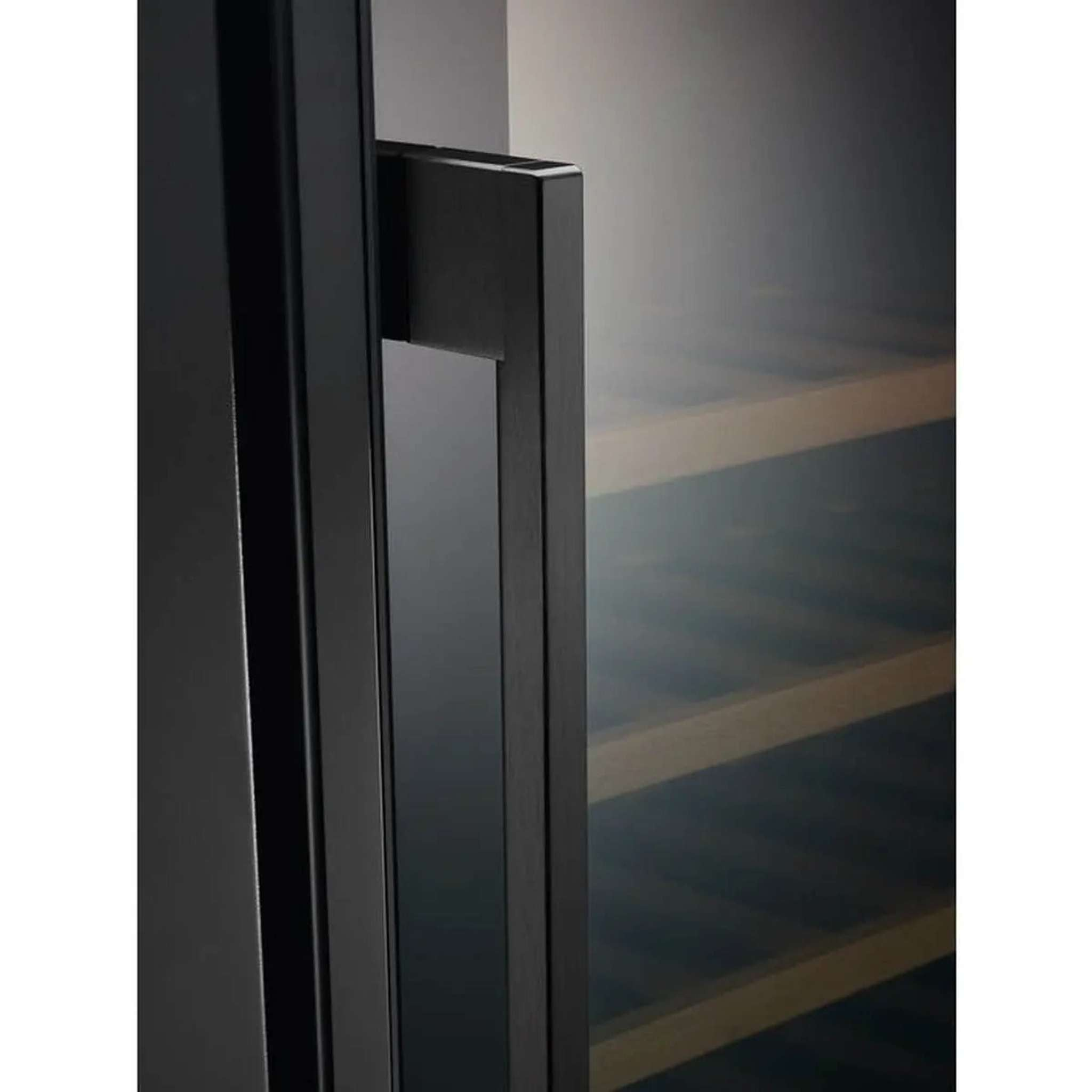 Primer plano de la puerta y el asa de un enfriador de vino negro. Estantes de madera visibles en el interior.