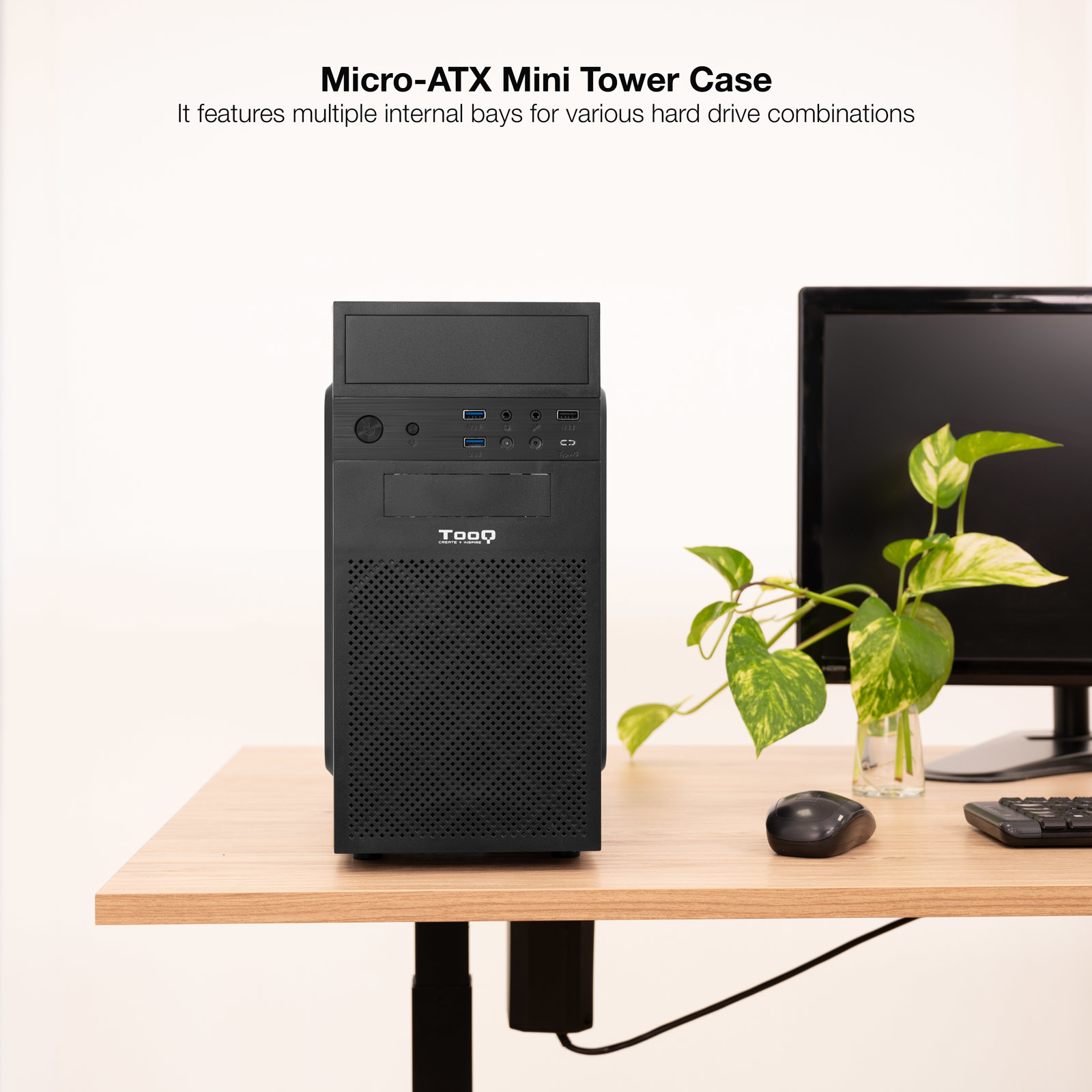 Un case per computer nero su un tavolo di legno, accanto a un monitor e una pianta.