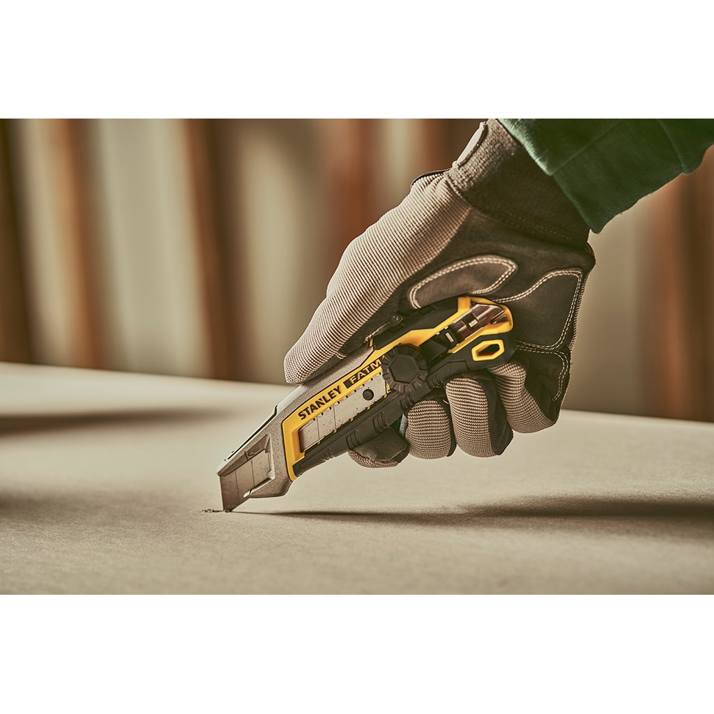 Hand mit Handschuh, die ein Stanley FatMax-Messer benutzt, um Material zu schneiden. Graue Handschuhe.