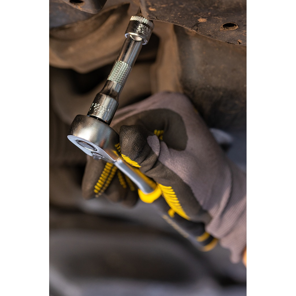 Una mano enguantada usando una llave de carraca para apretar un perno debajo de un coche.