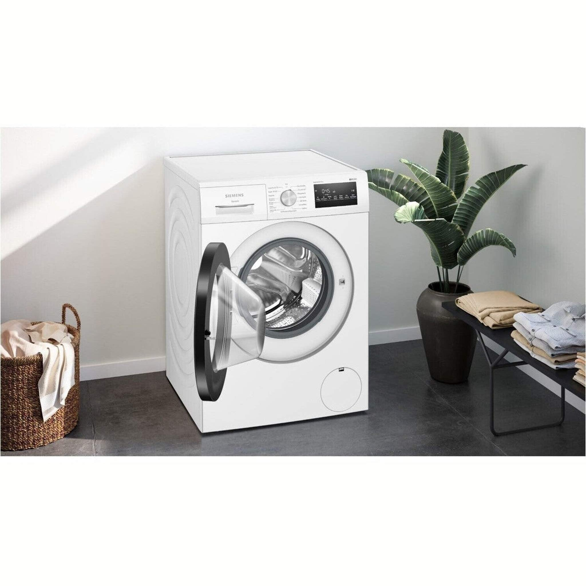 White washing machine with open door, laundry basket and plant.
