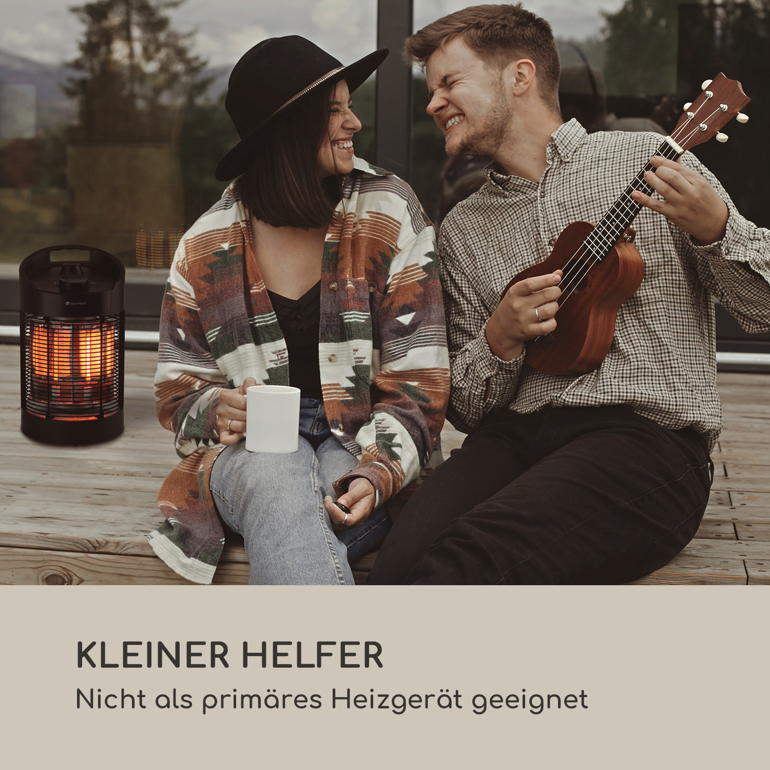 Una coppia seduta su una terrazza, sorridente, con un ukulele e un piccolo riscaldatore.