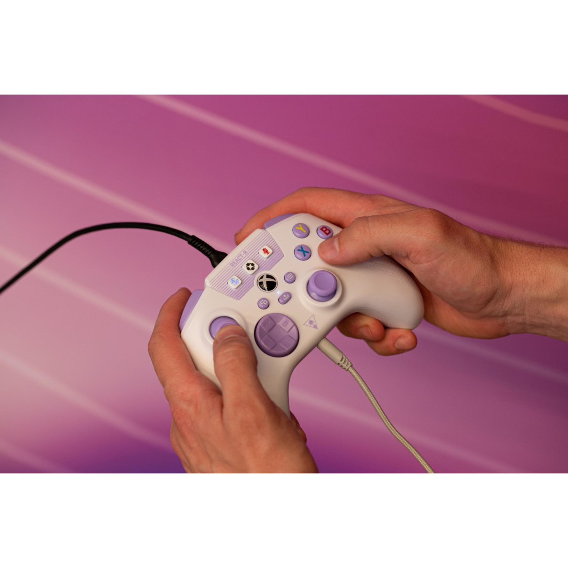 Persona che tiene in mano un controller per videogiochi bianco e viola. Pulsanti e stick sono visibili. Un cavo è collegato.