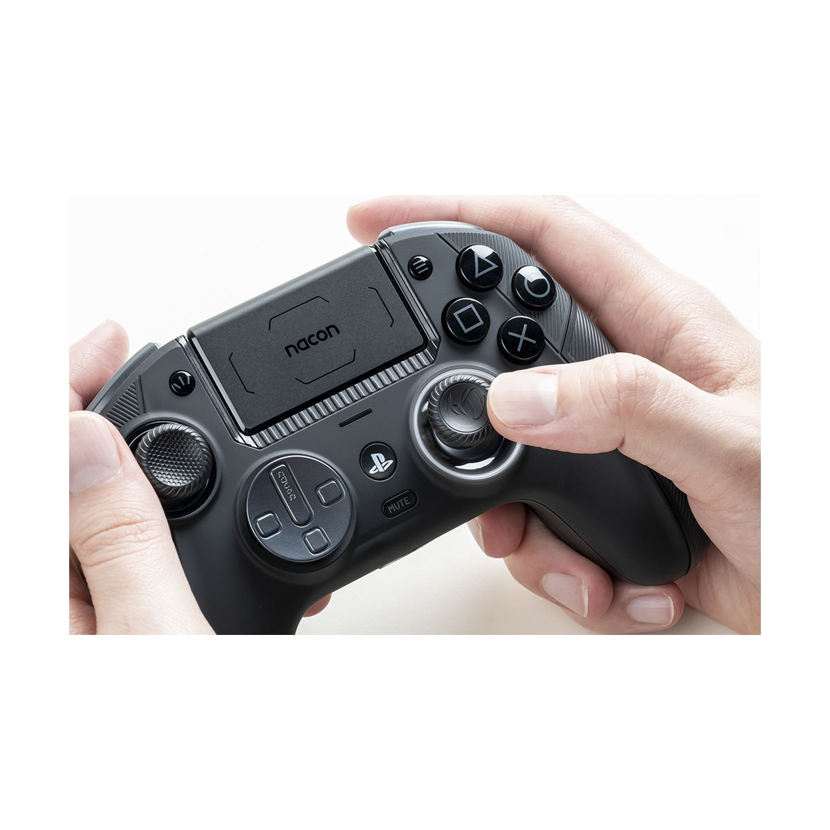 Dłonie osoby trzymającej czarny kontroler Playstation. Białe tło.