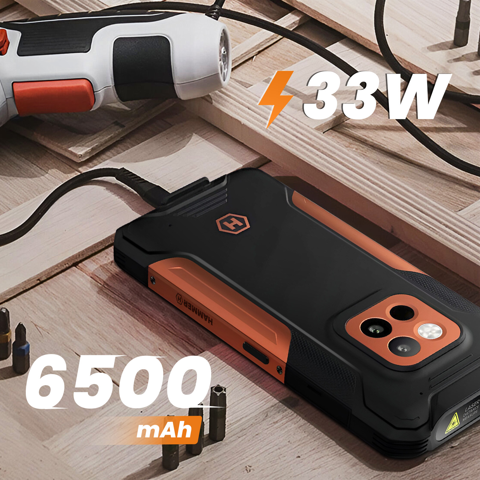 Schwarz-orangenes Smartphone beim Laden mit Bohrmaschine und Werkzeugen im Hintergrund, zeigt 6500 mAh und 33W.