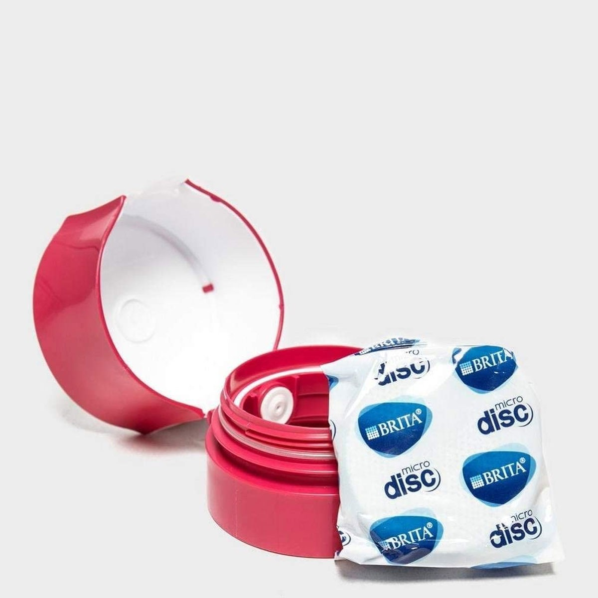 Tappo e interno di bottiglia d'acqua rosa con filtri a microdisco. Sfondo bianco.