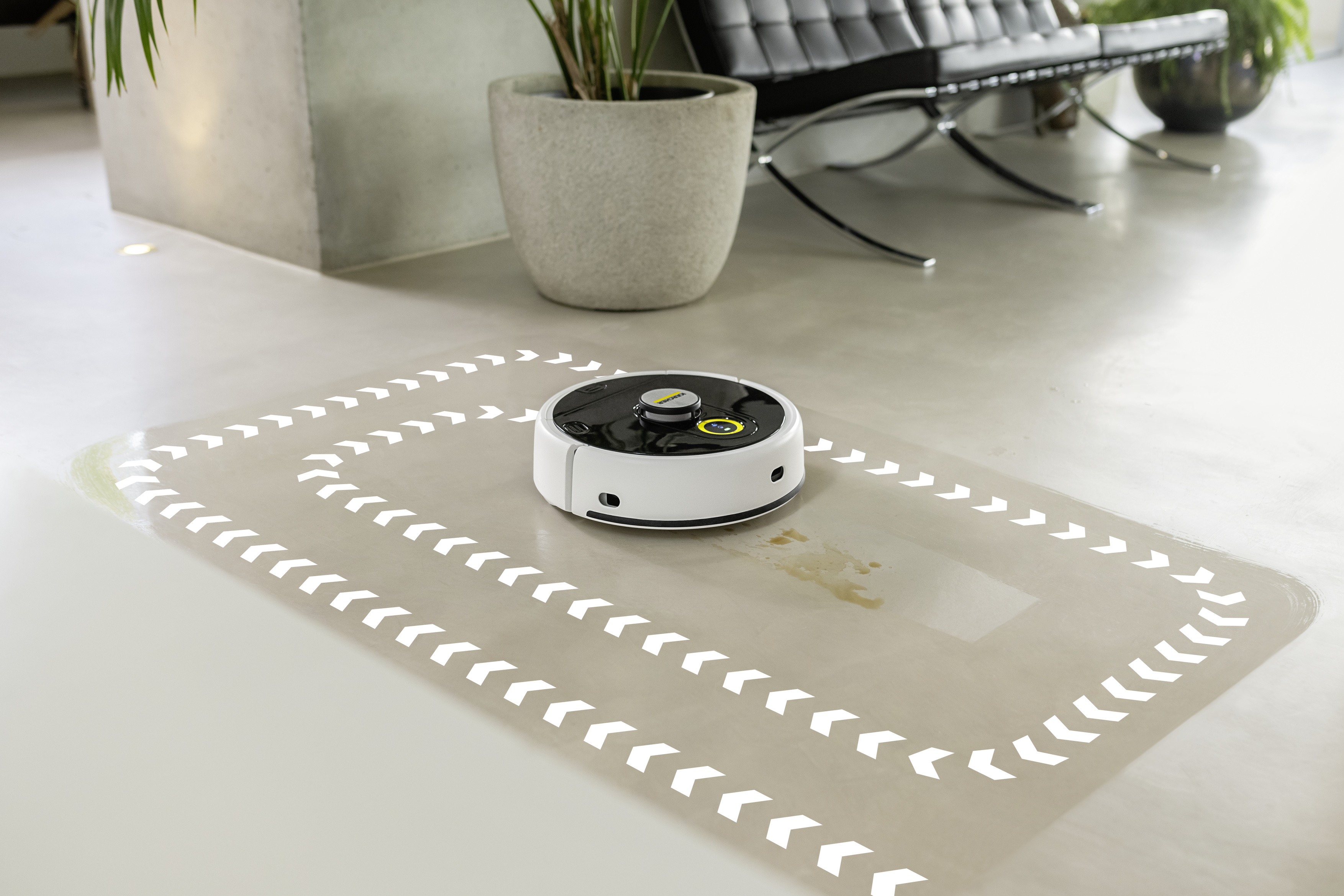 Biały odkurzacz robot sprzątający podłogę, podążając wyznaczoną ścieżką.