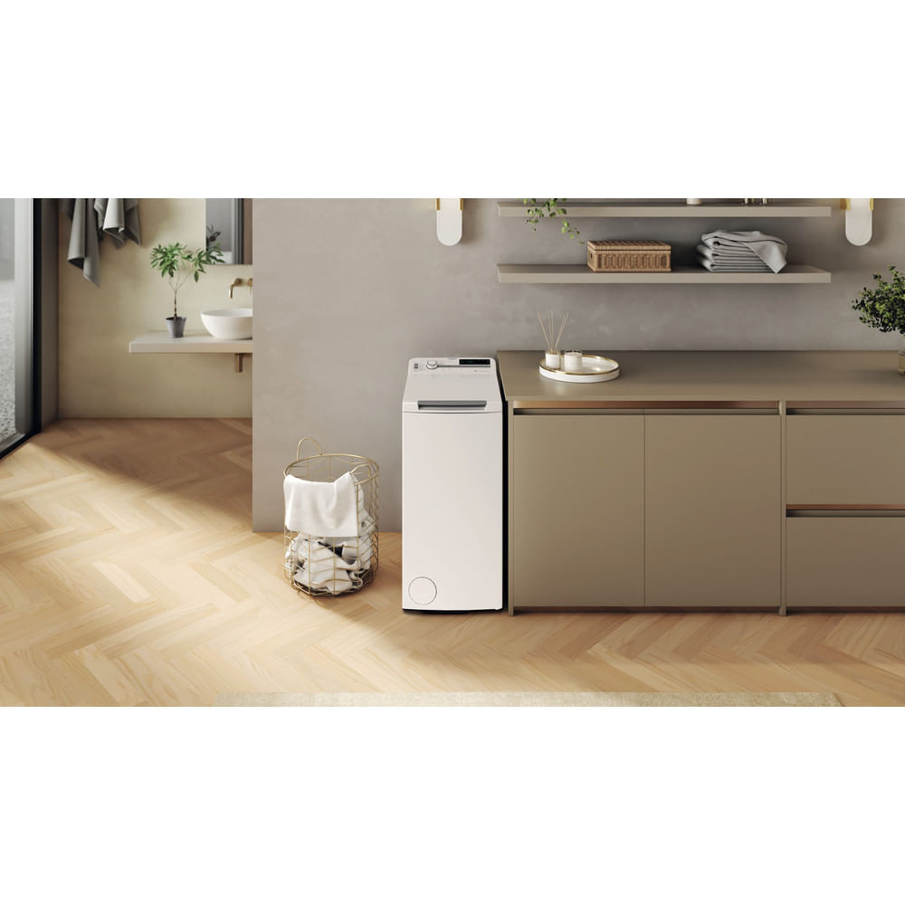 Pralnia z białą pralką ładowaną od góry, szafką i koszem na pranie.