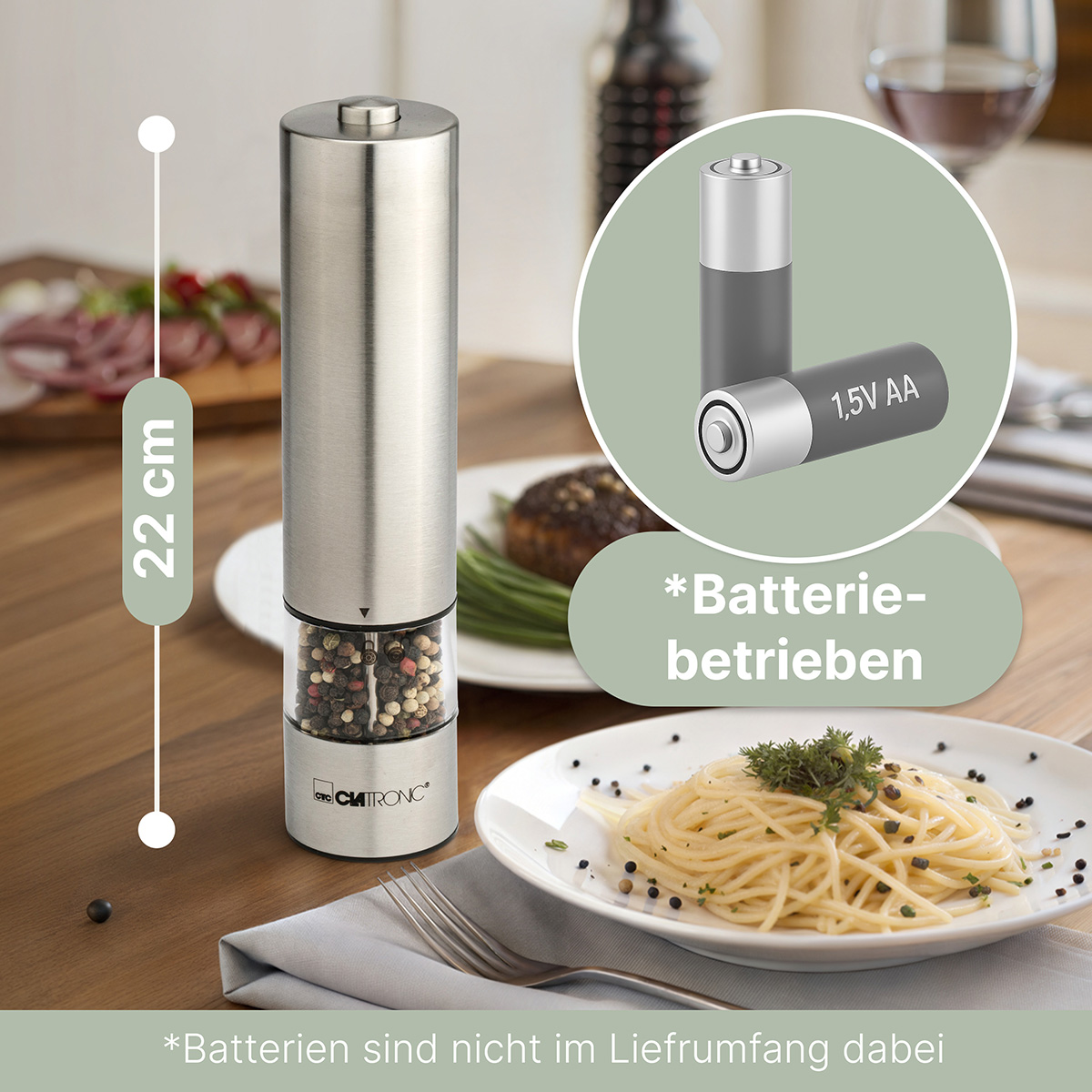 Srebrny młynek do pieprzu z makaronem i widelcem na talerzu. Baterie AA obok.
