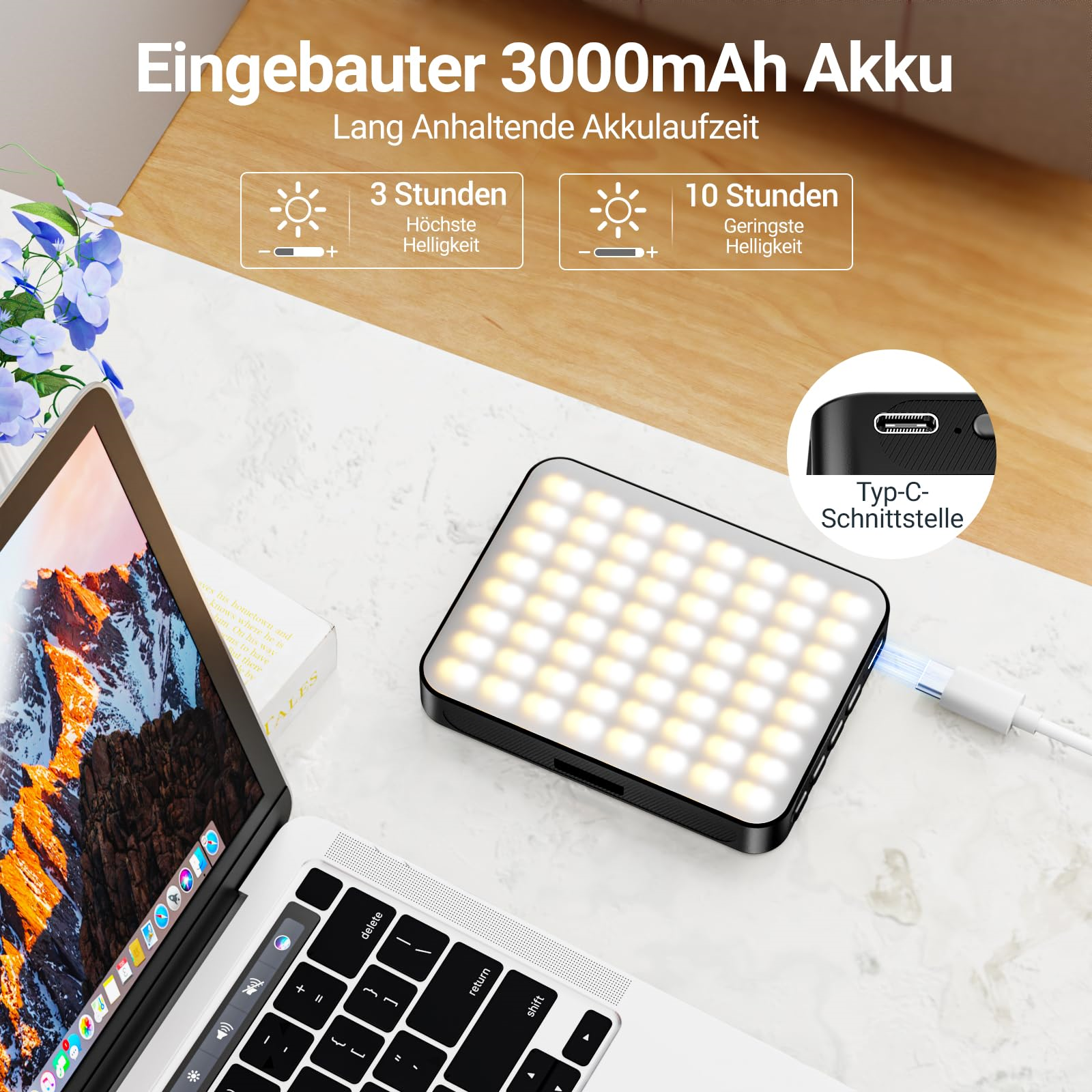 Ein schwarz-weißes tragbares Licht mit Ladekabel neben einem Tablet und einem Laptop.