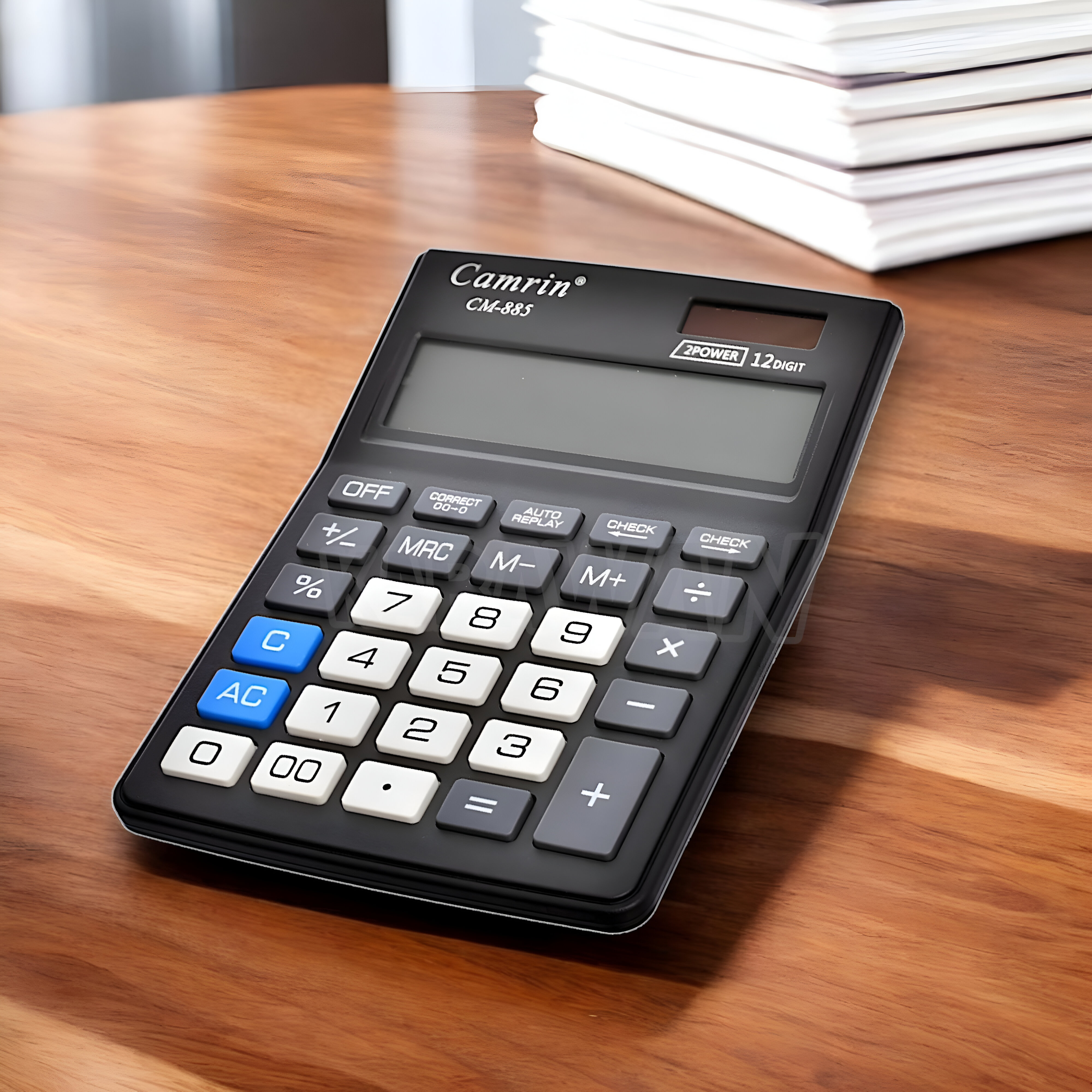 Calculadora negra con botones blancos sobre una mesa de madera. Un montón de papel blanco en el fondo.