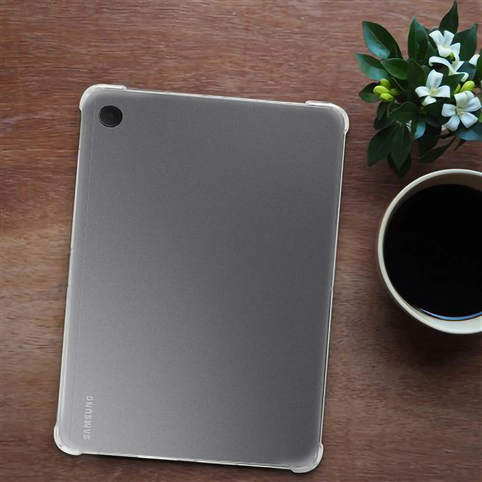 Ein Tablet in einer Hülle mit einer Pflanze und einer Tasse auf einer Holzoberfläche.