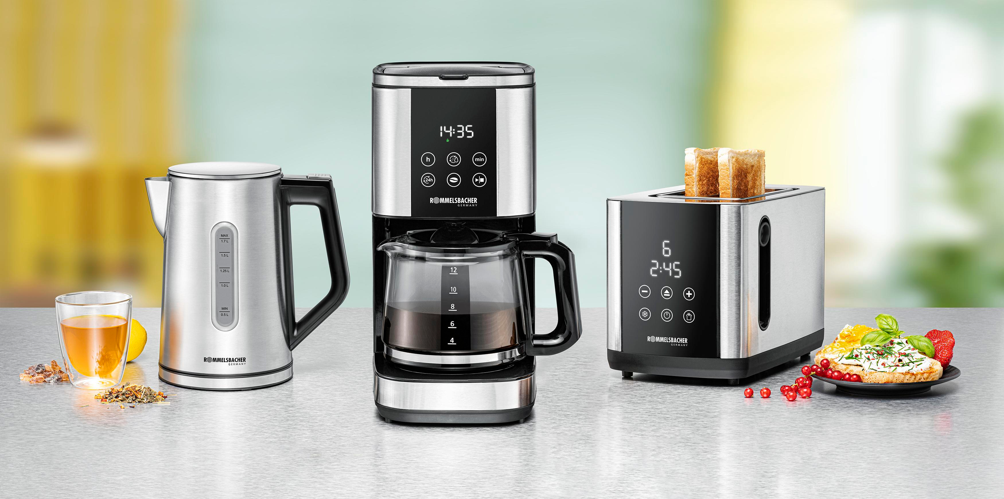 Czajnik, ekspres do kawy i toster z jedzeniem na stole.