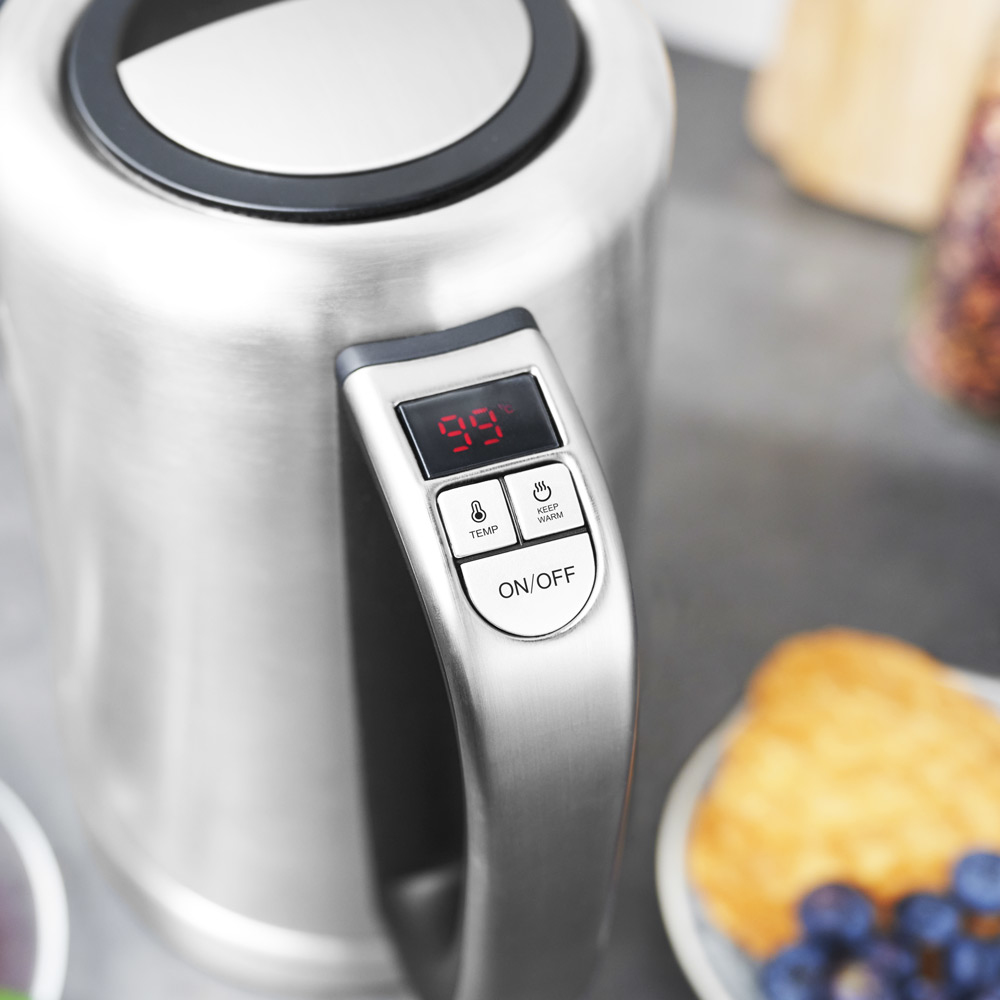 Elektryczny czajnik ze stali nierdzewnej z cyfrowym wyświetlaczem pokazującym 99 stopni. Widoczne przyciski On/Off i temp.