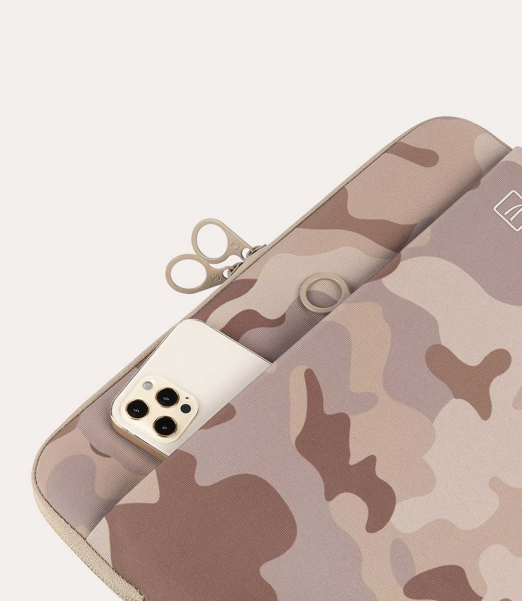 Primer plano de un teléfono en una funda con estampado de camuflaje, con cremallera y un anillo.