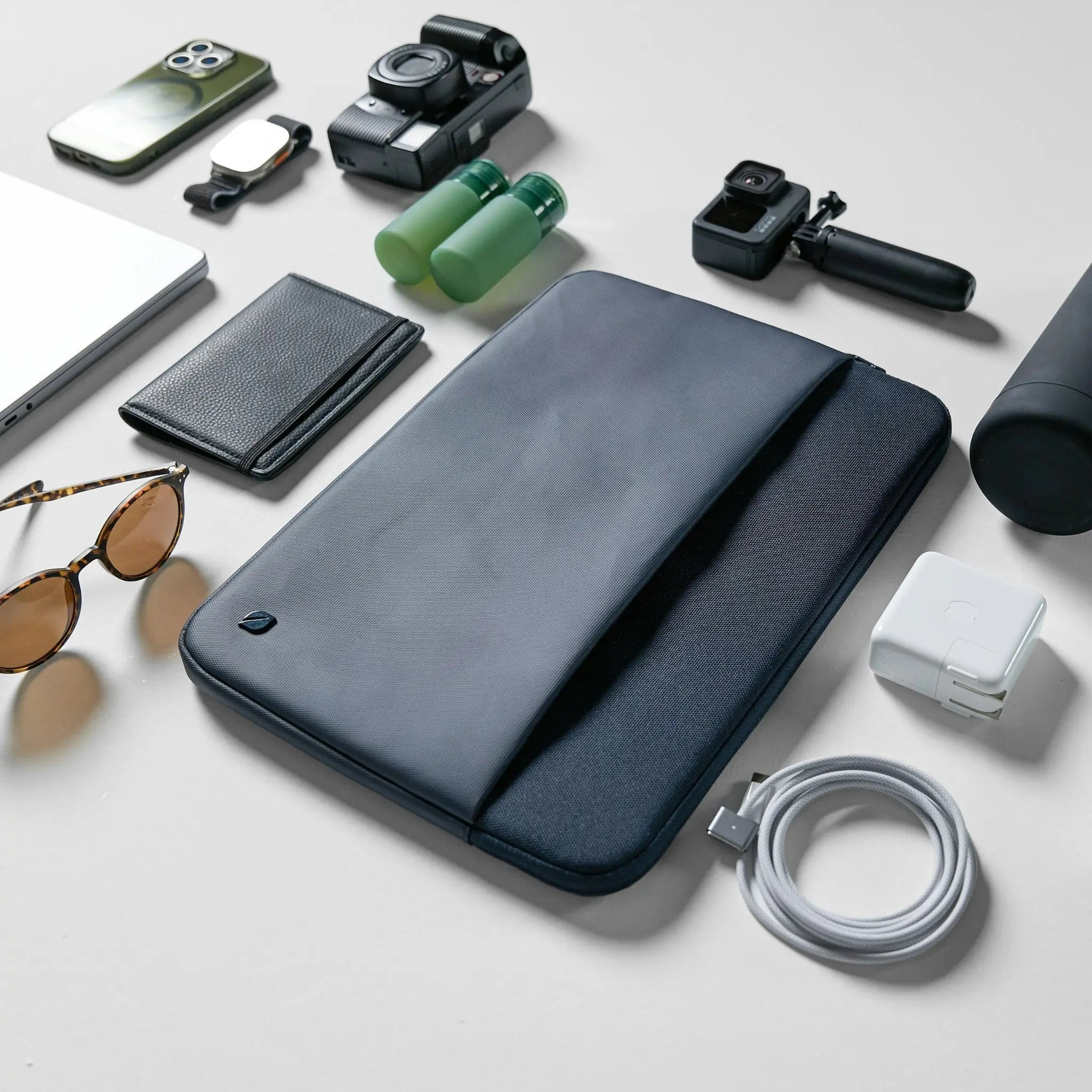 Una collezione di oggetti tecnologici, tra cui una custodia, un telefono, una fotocamera e un caricabatterie.