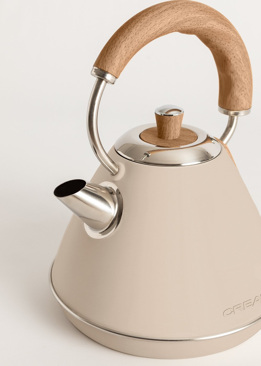 Una tetera color crema con asa de madera y base y boquilla plateadas.