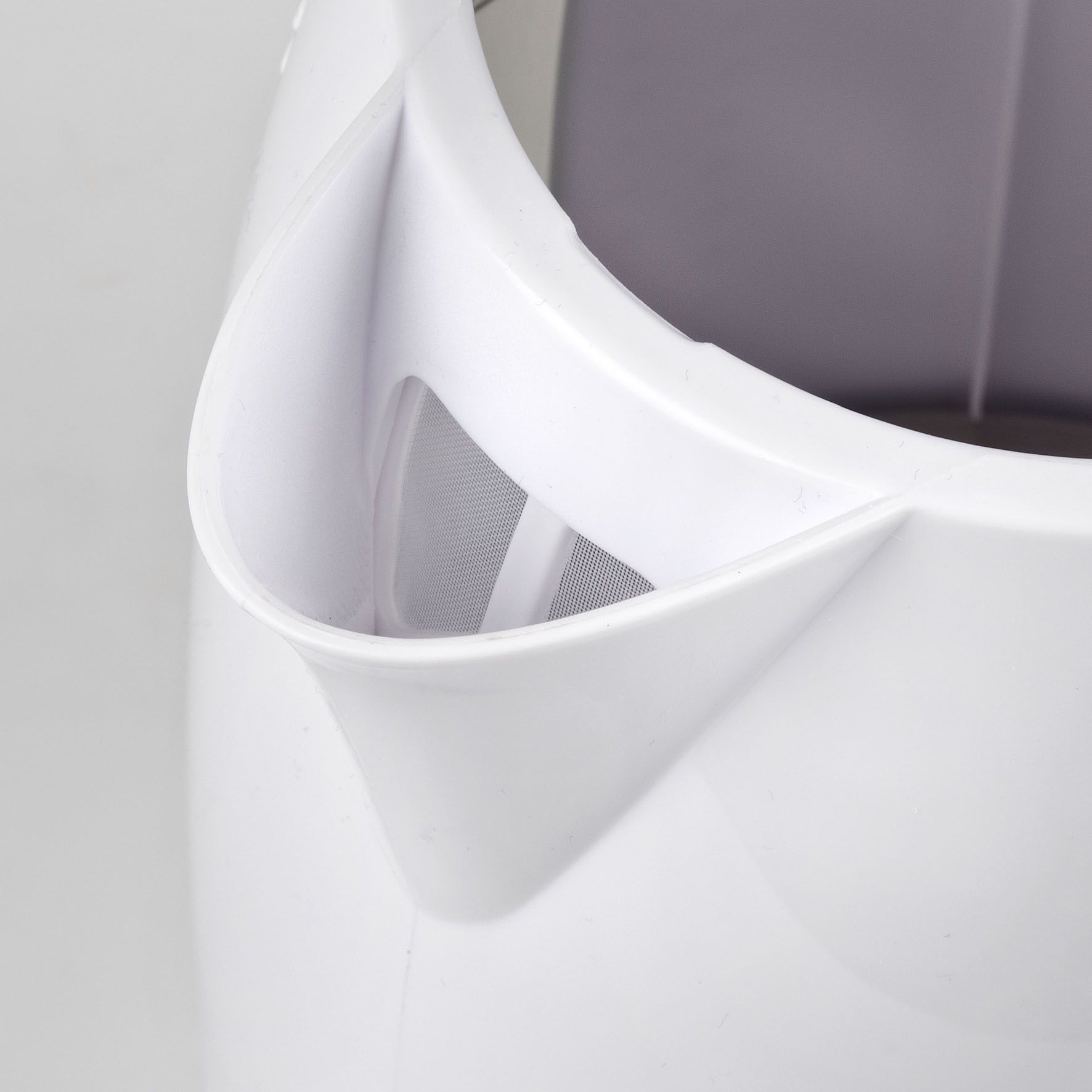 Zbliżenie wylewu białego dzbanka z tworzywa sztucznego z filtrem siatkowym w środku.